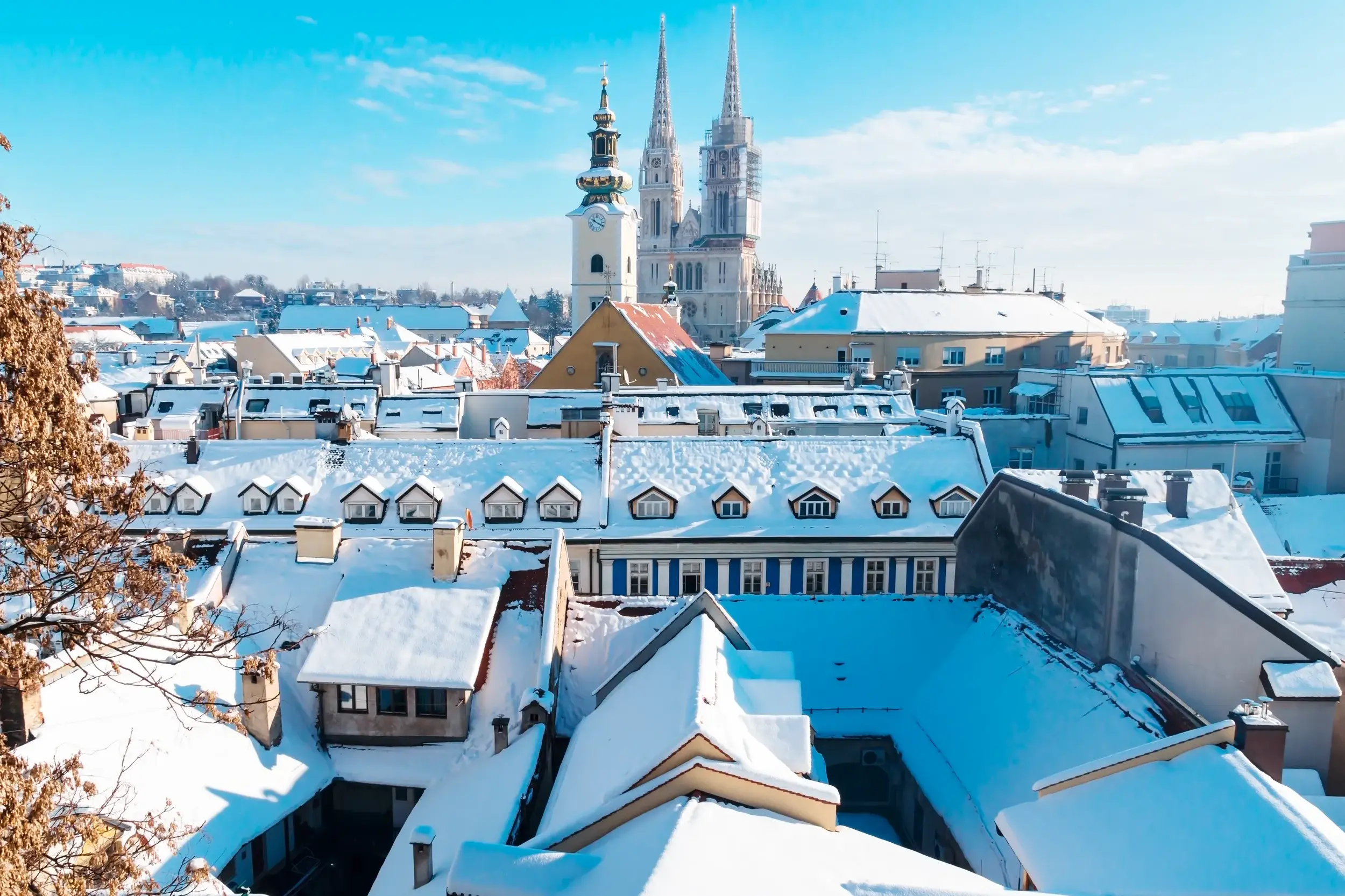 Verschneite Dächer der Altstadt von Zagreb an einem sonnigen Wintertag mit der neugotischen Kathedrale im Hintergrund.