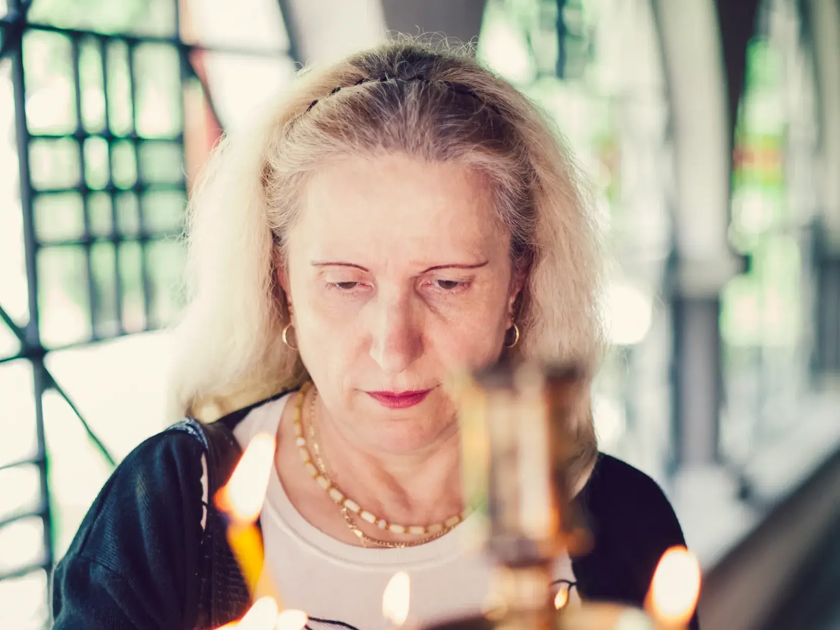 Eine Dame betrachtet nachdenklich die Flammen von Kerzen in einem der berühmten Klöster Bulgariens.