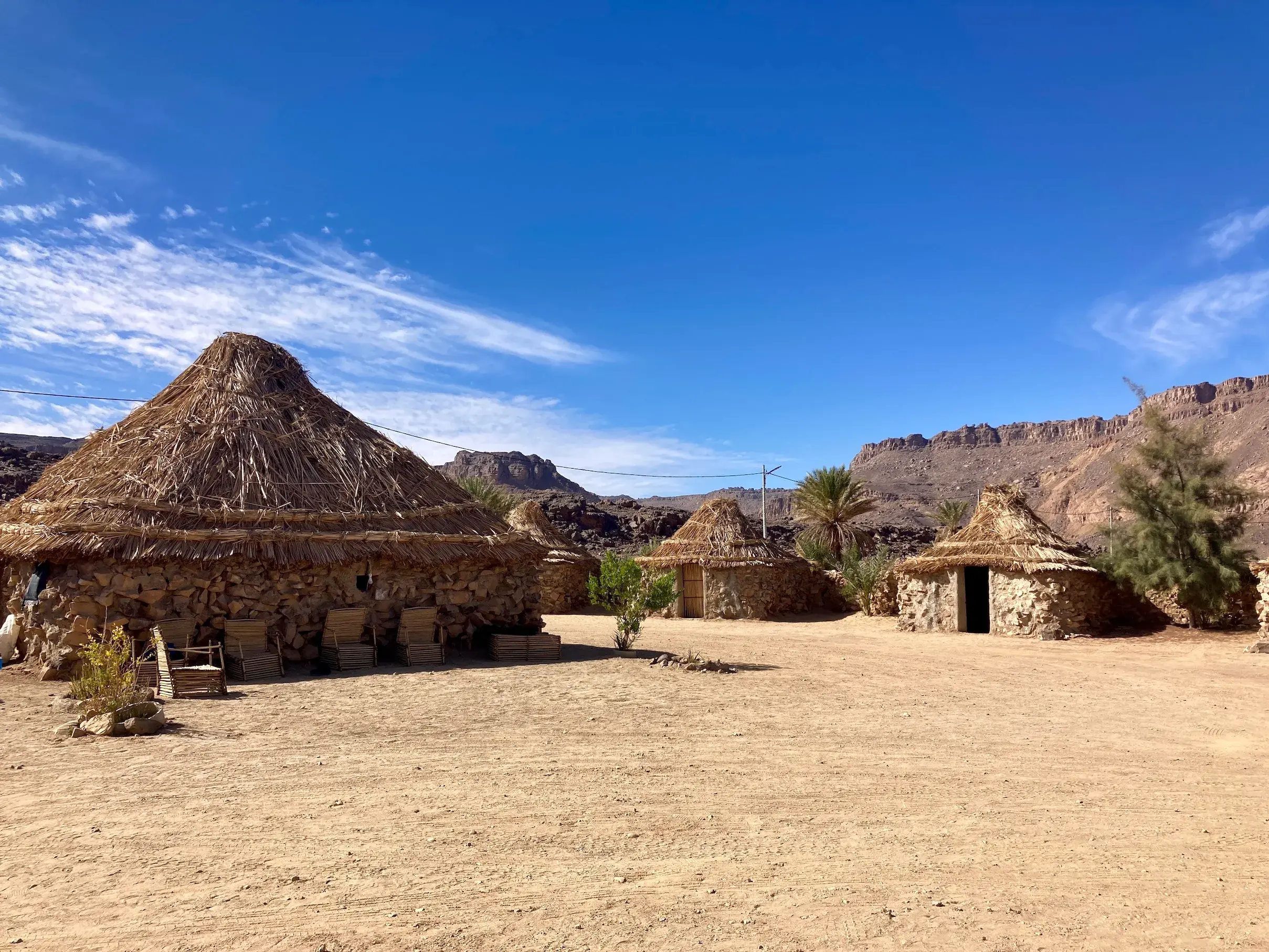 Traditionelles Camp mit Zeriba-Hütten im Tuareg-Dorf Iherir vor einer Felskulisse im Tassili n'Ajjer Nationalpark.