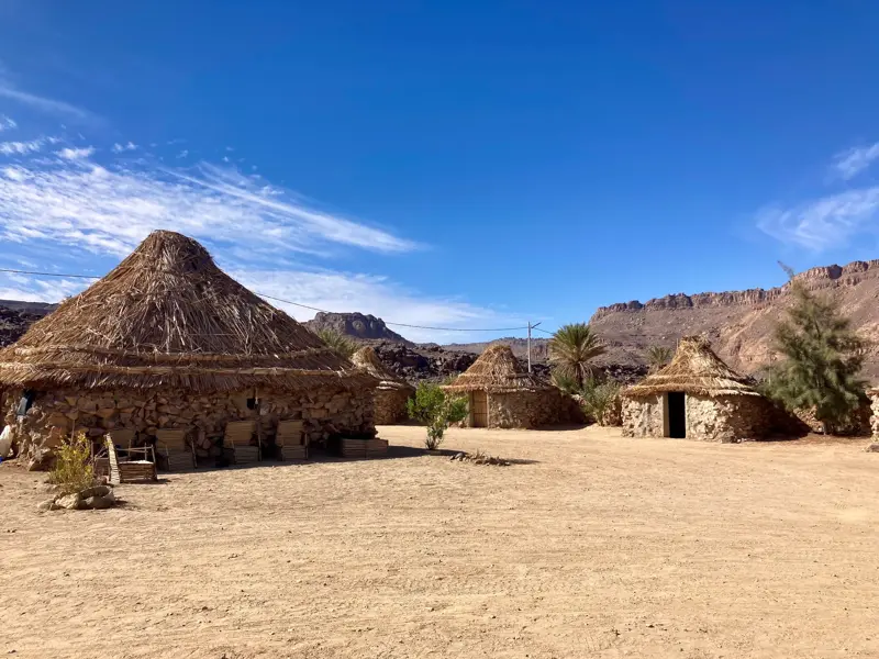 Traditionelles Camp mit Zeriba-Hütten im Tuareg-Dorf Iherir vor einer Felskulisse im Tassili n'Ajjer Nationalpark.