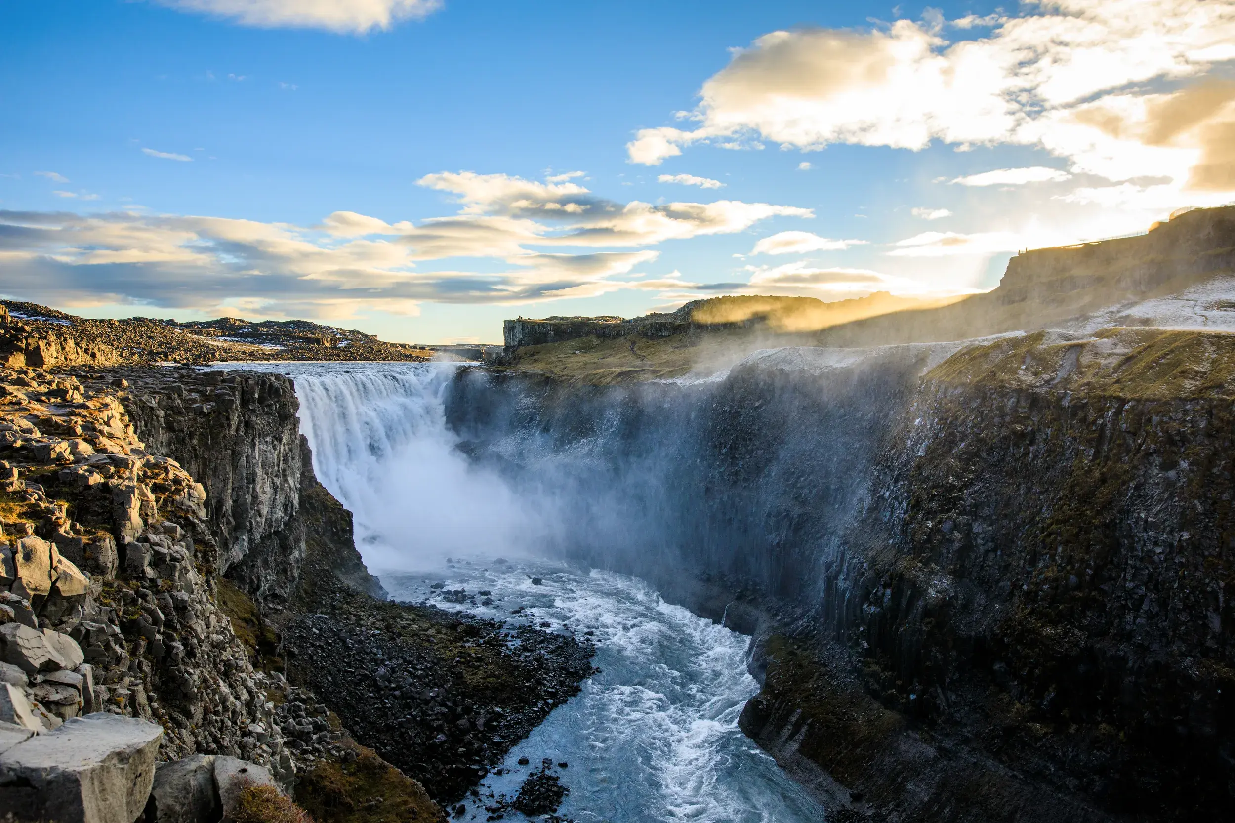 Der mächtige Dettifoss Wasserfall in Island stürzt bei Sonnenuntergang tosend in eine dunkle, felsige Schlucht.