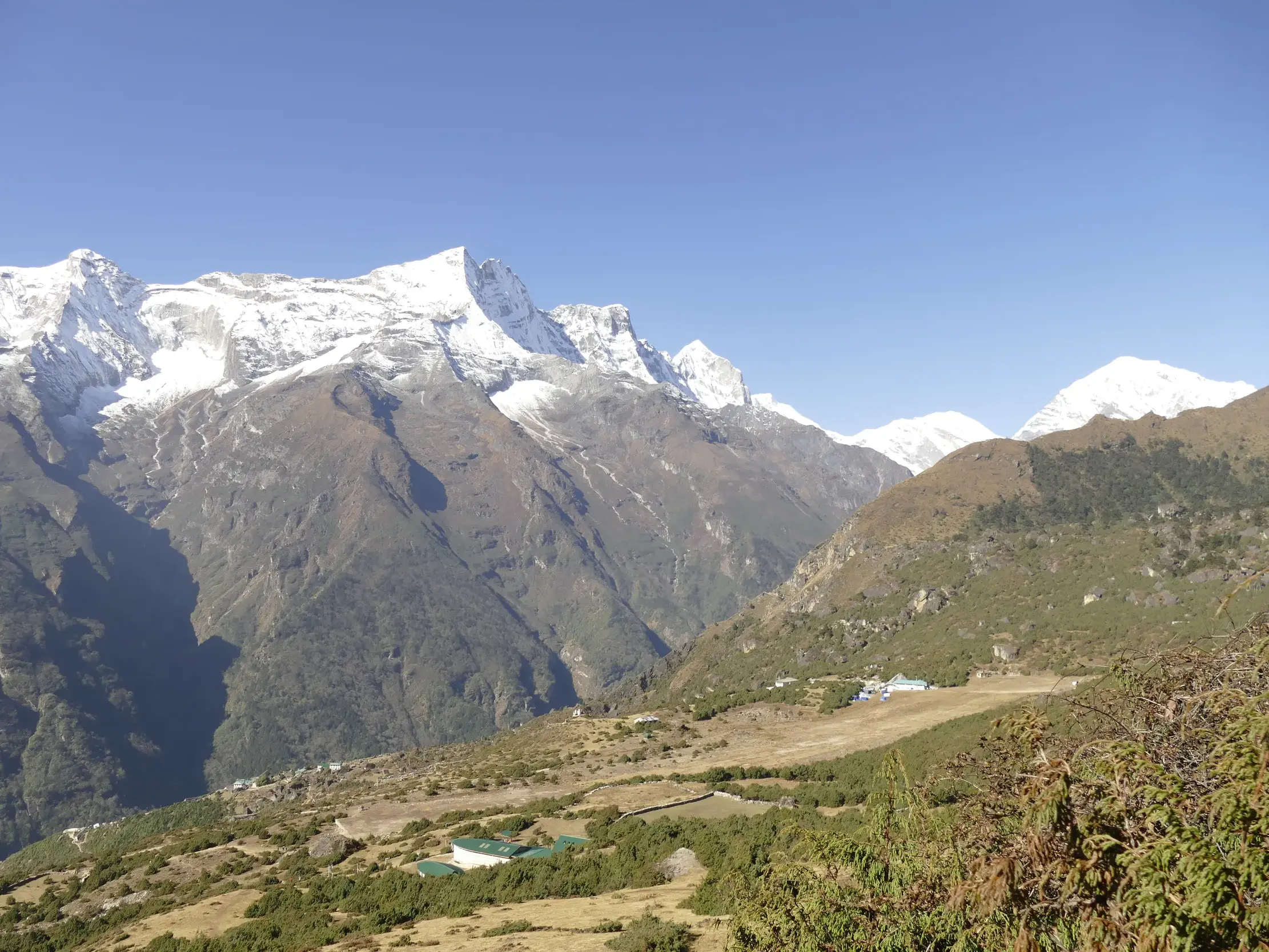 Blick von oberhalb Namche Bazars auf die schneebedeckten Himalaya-Gipfel in der Khumbu-Region Nepals bei Sonnenschein.