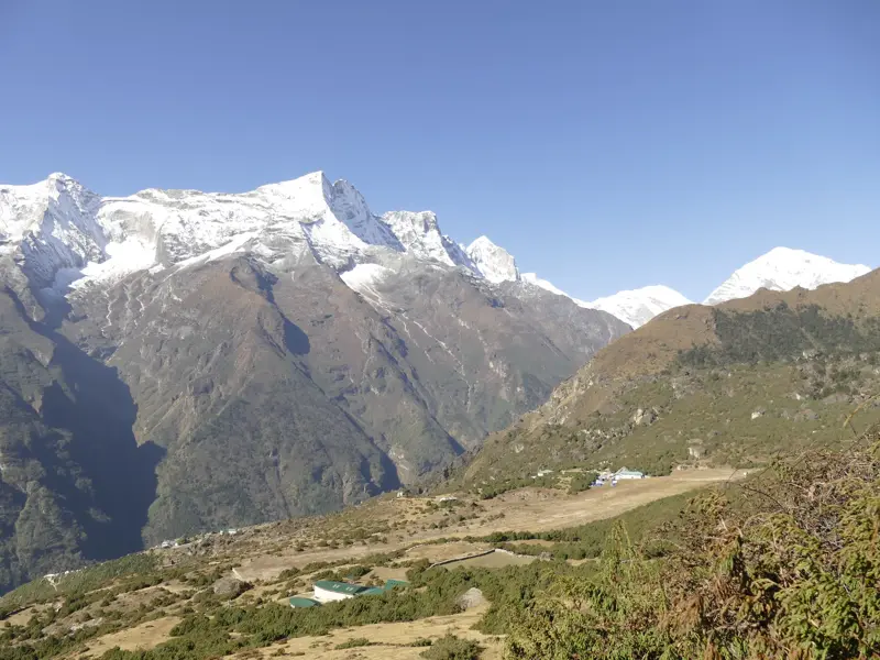 Blick von oberhalb Namche Bazars auf die schneebedeckten Himalaya-Gipfel in der Khumbu-Region Nepals bei Sonnenschein.