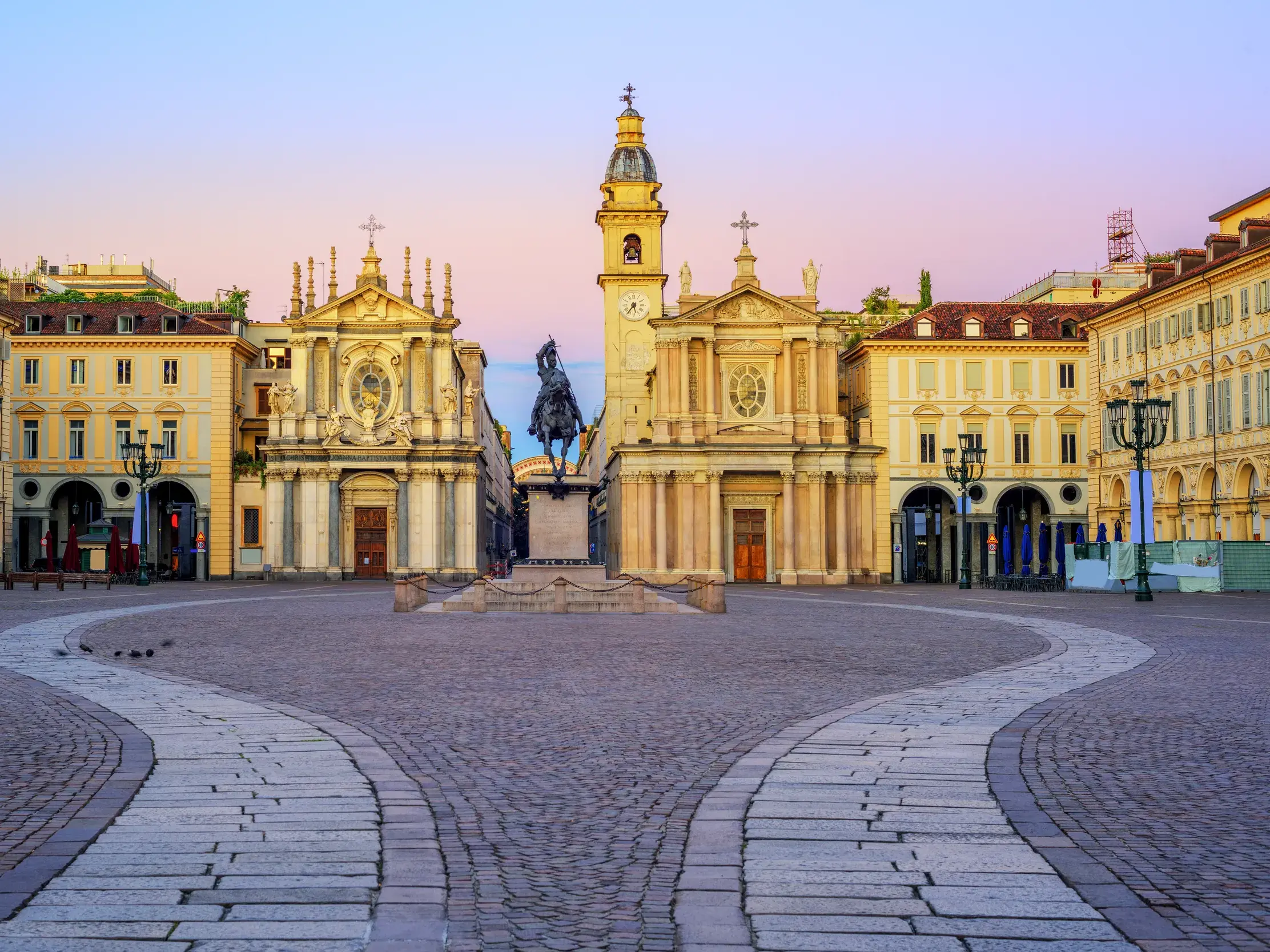 Die barocke Pracht von Turin auf einem großzügigen Platz mit Zwillingskirchen und Reiterstandbild im Morgenlicht.