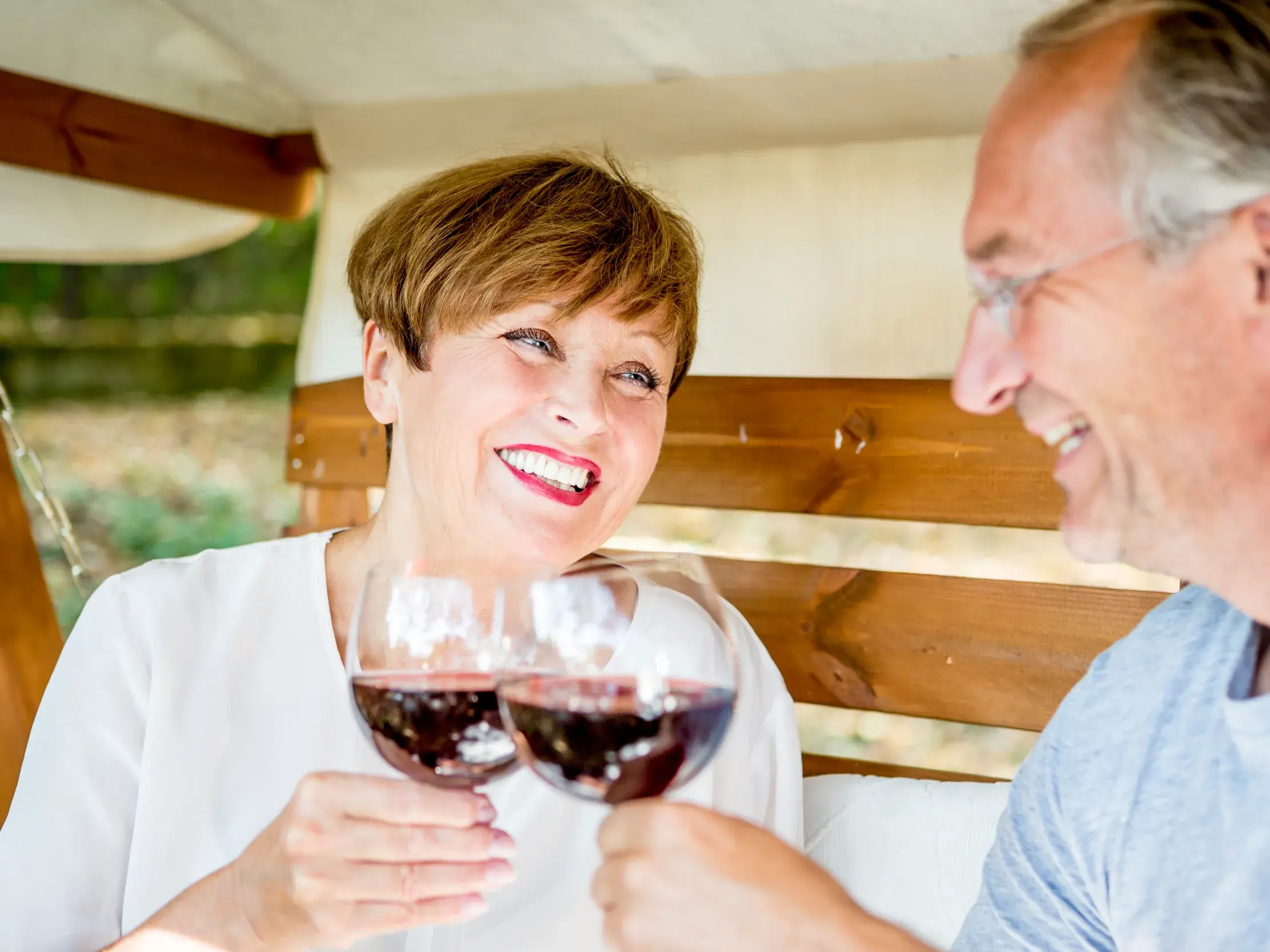 Ein lächelndes Paar genießt die gemeinsame Zeit bei einem Glas Rotwein während ihrer geruhsamen Studiosus-Reise in Griechenland.