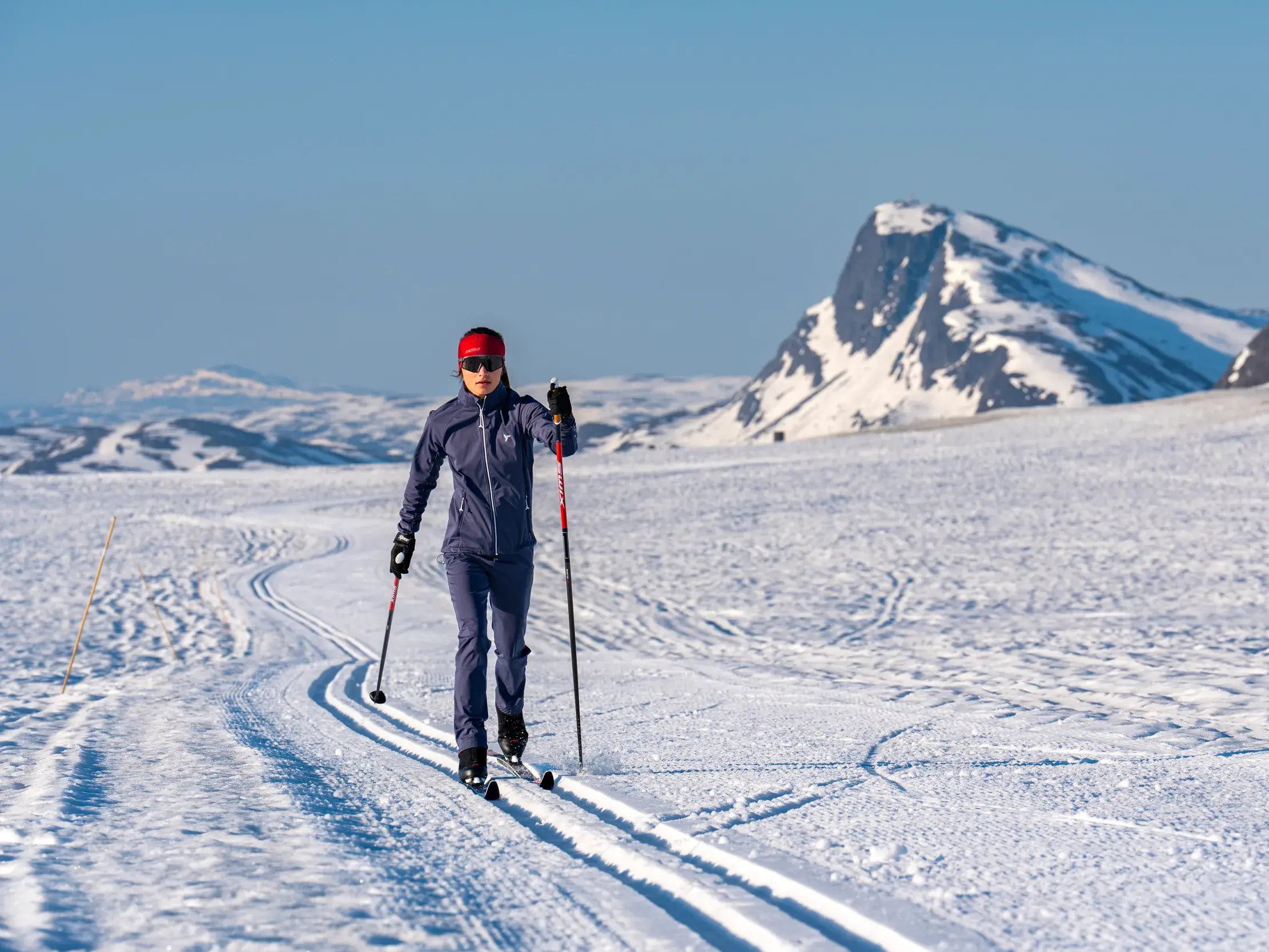 Langläuferin auf einer präparierten Loipe in der weiten Schneelandschaft von Valdres mit Panoramablick auf Jotunheimen.