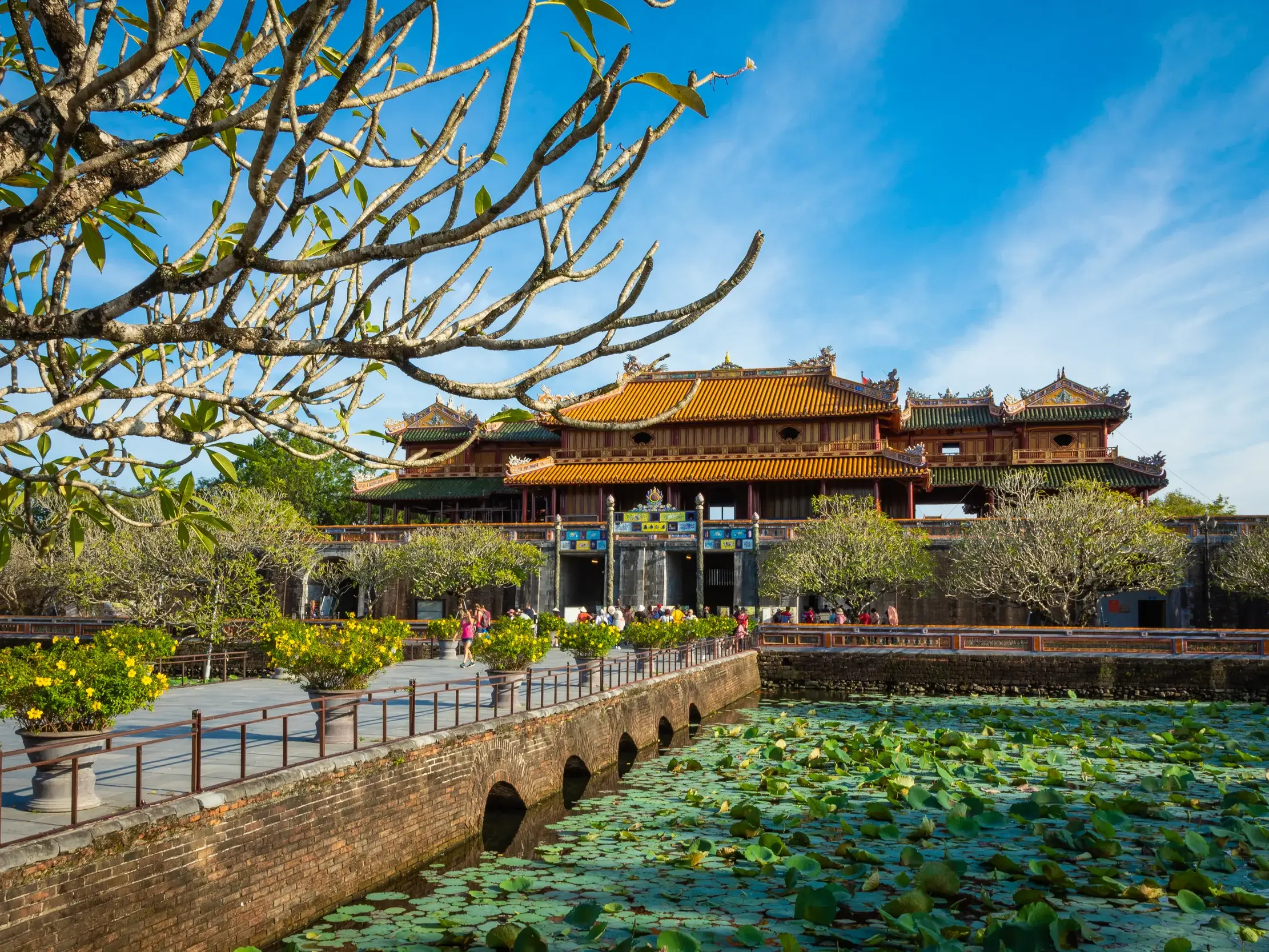Sonniger Blick auf das Eingangstor der Kaiserstadt in Hue, Vietnam, über eine Brücke, die einen von Seerosen bedeckten Graben quert.