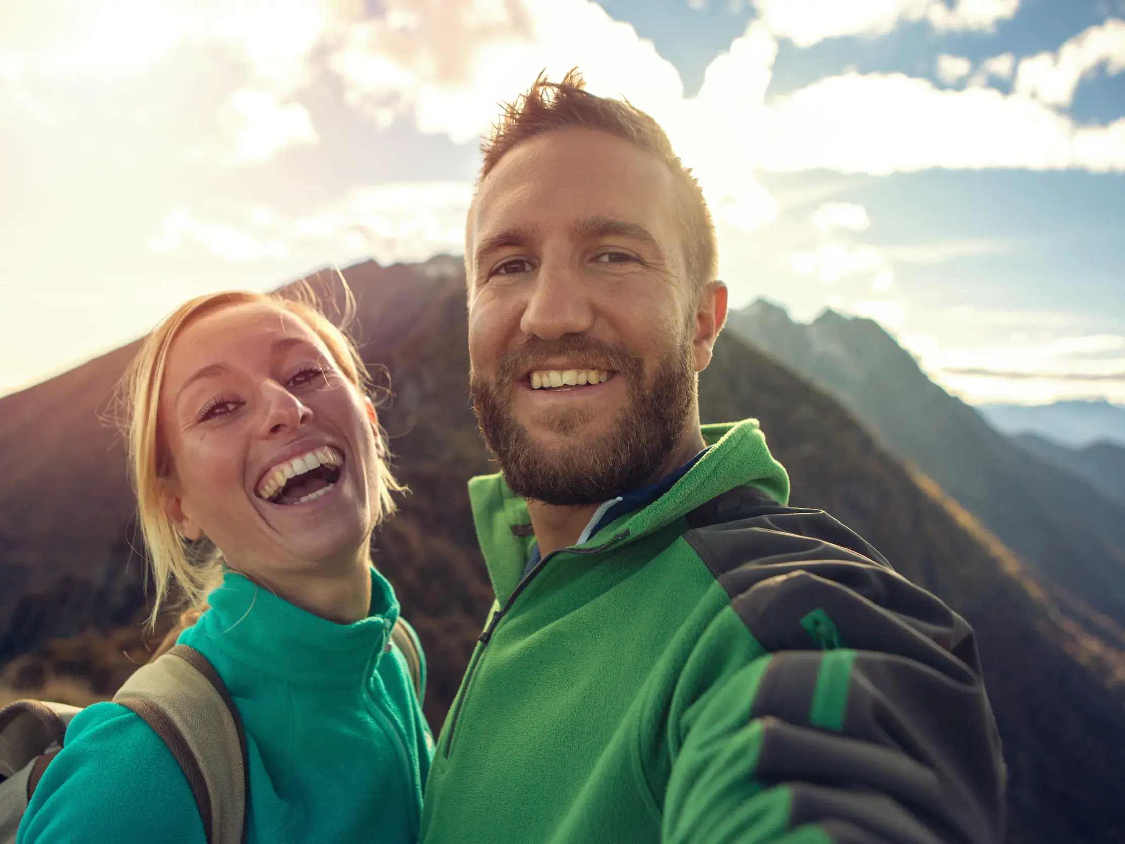 Ein glückliches Paar macht ein fröhliches Selfie während einem Spaziergang auf ihrer Kleingruppenreise in Island bei Sonnenschein.