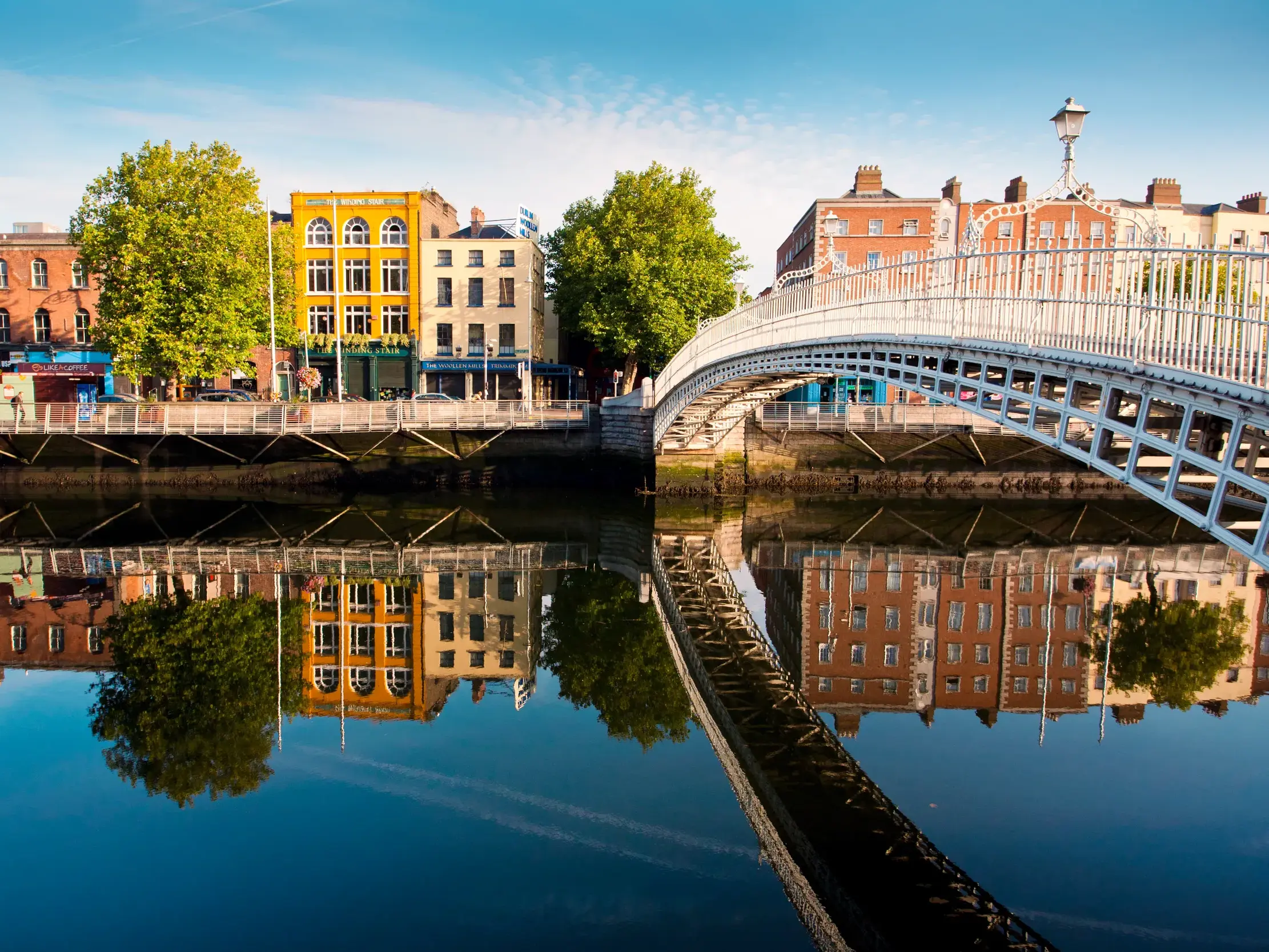 Die Ha'penny Bridge, eines der Wahrzeichen Dublins spiegelt sich malerisch im Wasser der Liffey.