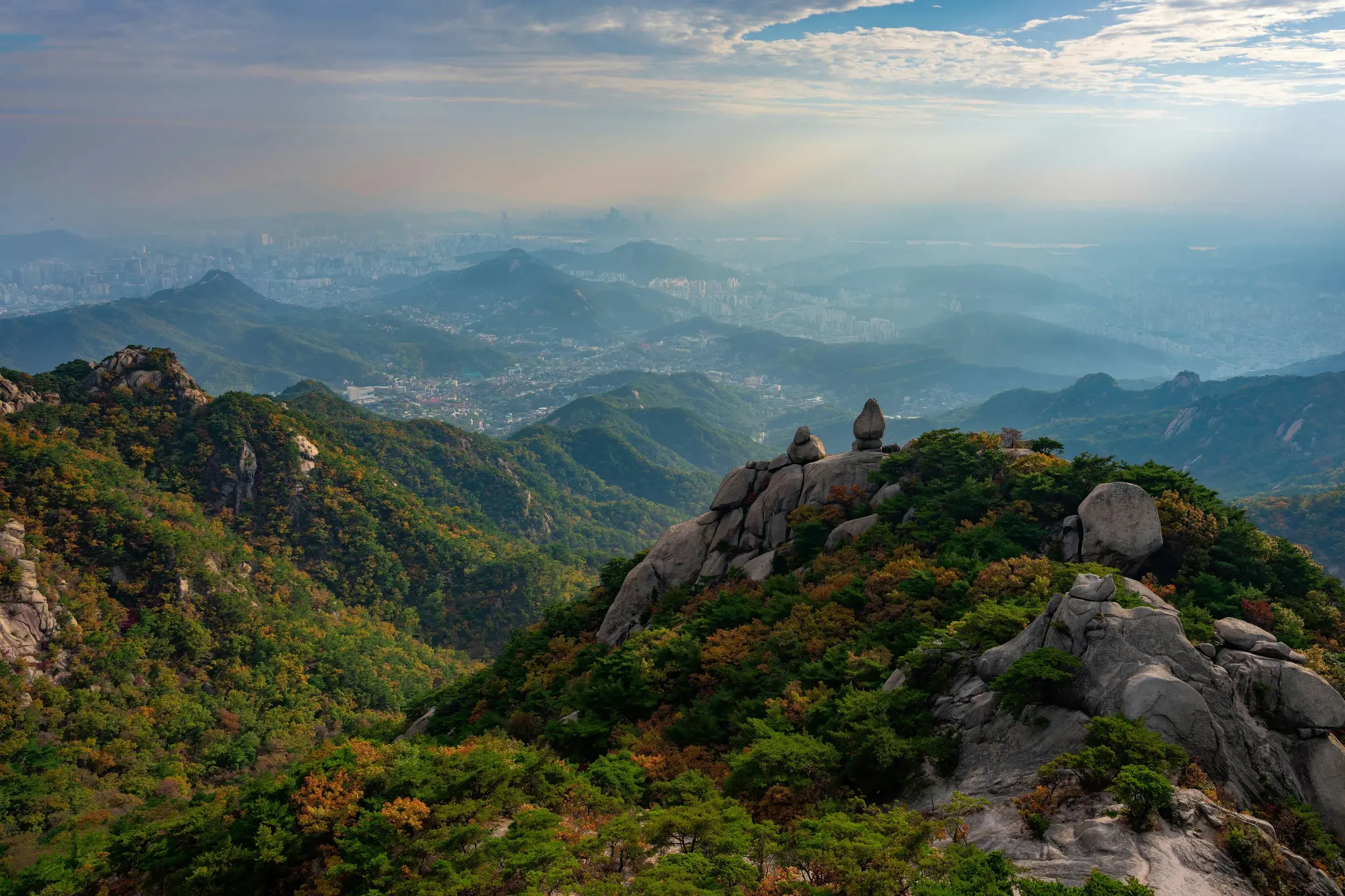 Panoramablick von den Granitfelsen des Bukhansan-Nationalparks auf die im Dunst liegende Metropole Seoul in Südkorea.