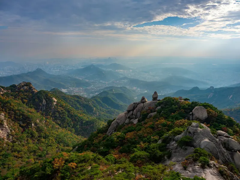 Panoramablick von den Granitfelsen des Bukhansan-Nationalparks auf die im Dunst liegende Metropole Seoul in Südkorea.