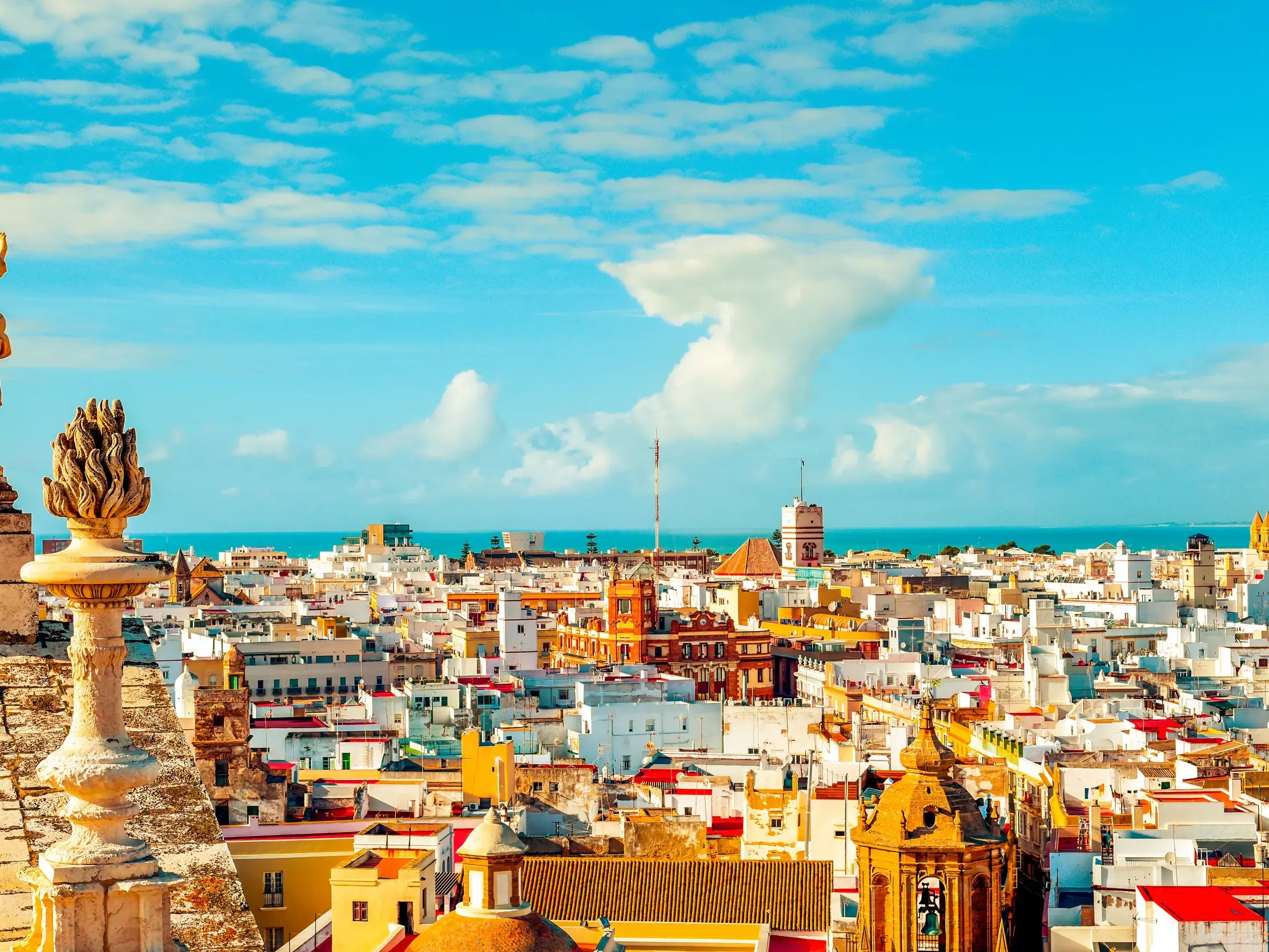 Sonniger Panoramablick von einer Kathedrale über die weißen Häuser der Altstadt von Cádiz bis zum blauen Atlantik.