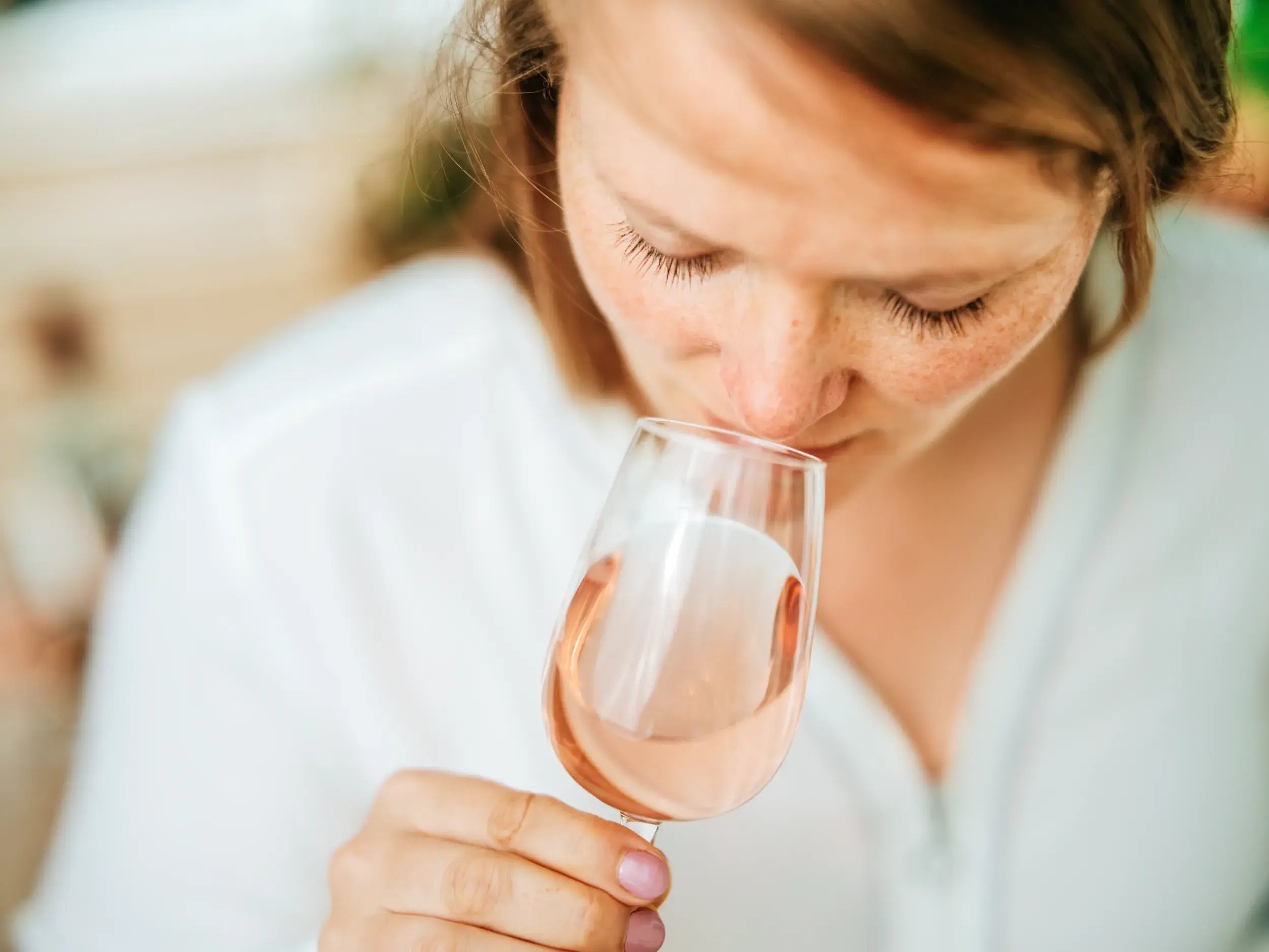 Eine Frau riecht mit geschlossenen Augen am Bouquet eines Glases Roséwein während einer Weinprobe auf einem Weingut auf Rhodos.
