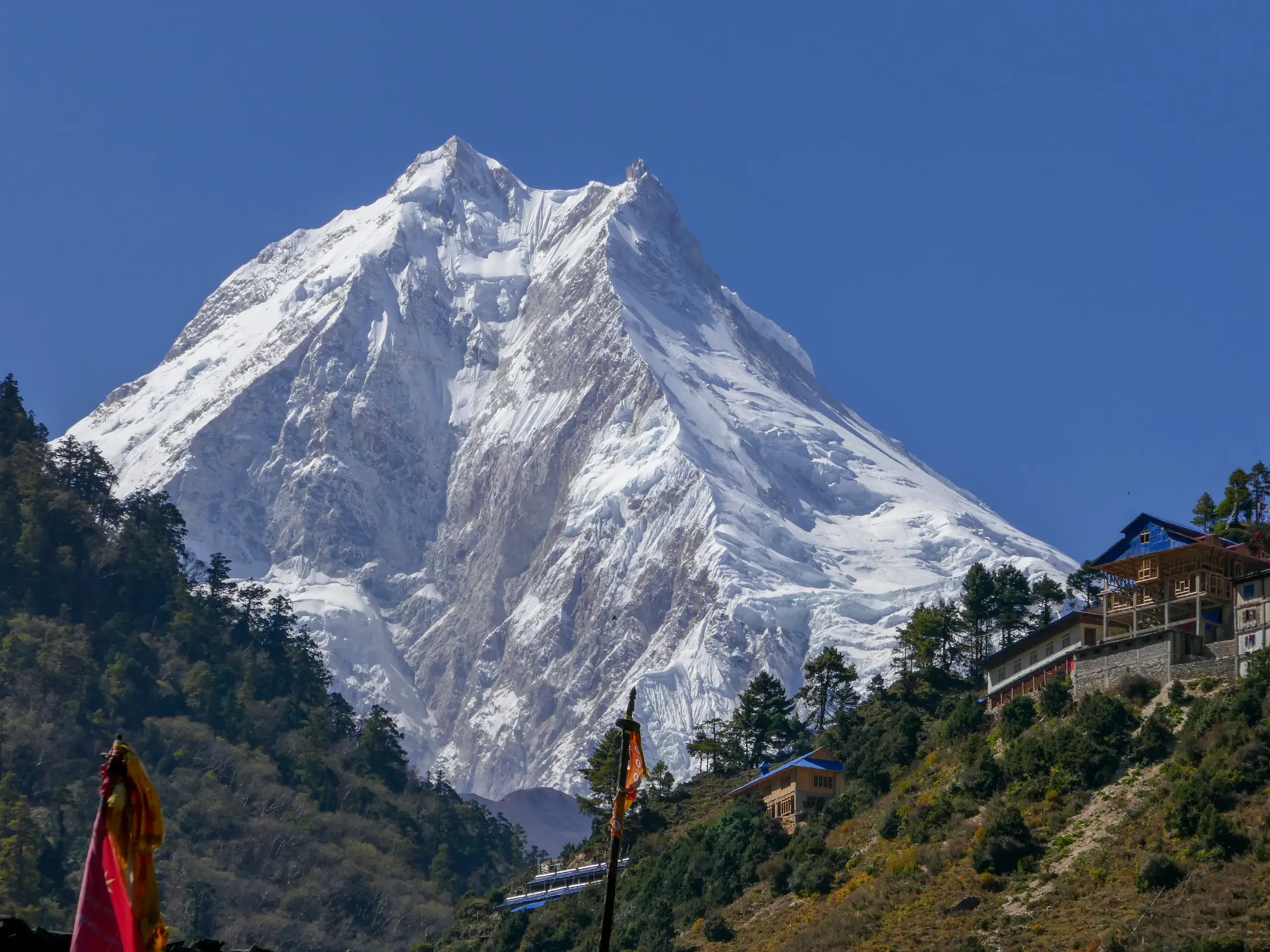 Der schneebedeckte Gipfel des Manaslu im Himalaya überragt eine Lodge im Bergdorf Lho während einer Trekking-Reise in Nepal.