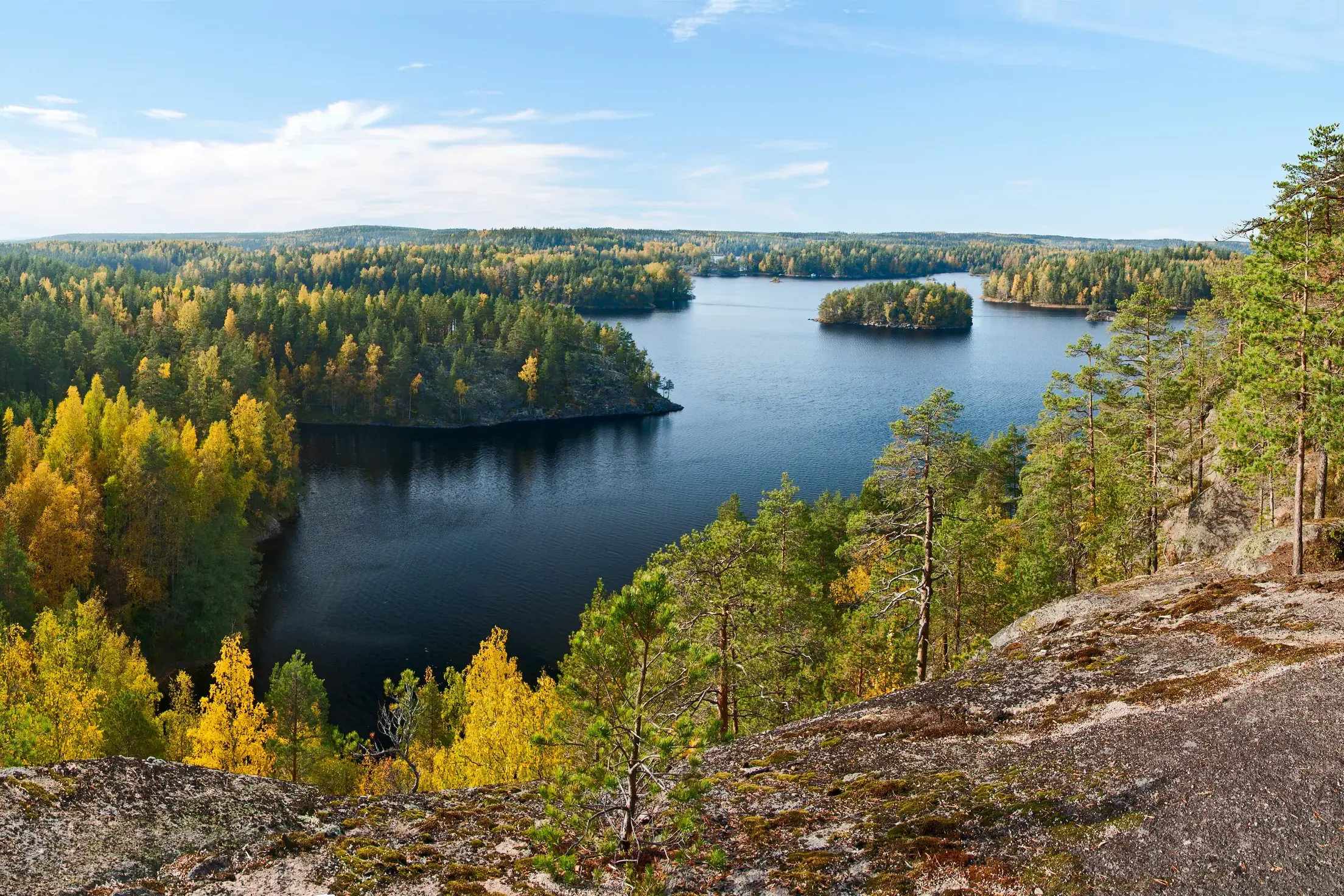 Panoramablick vom Aussichtspunkt Katajavuori auf einen See und die bunten Herbstwälder des Repovesi-Nationalparks.