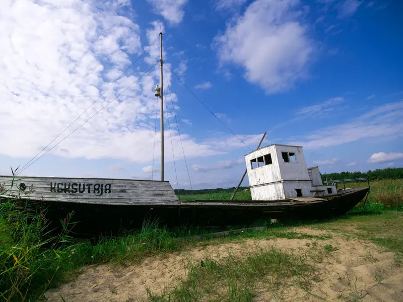 Altes, verwittertes Fischerboot auf einer sandigen Wiese an der estnischen Küste im Lahemaa-Nationalpark bei Sonnenschein.