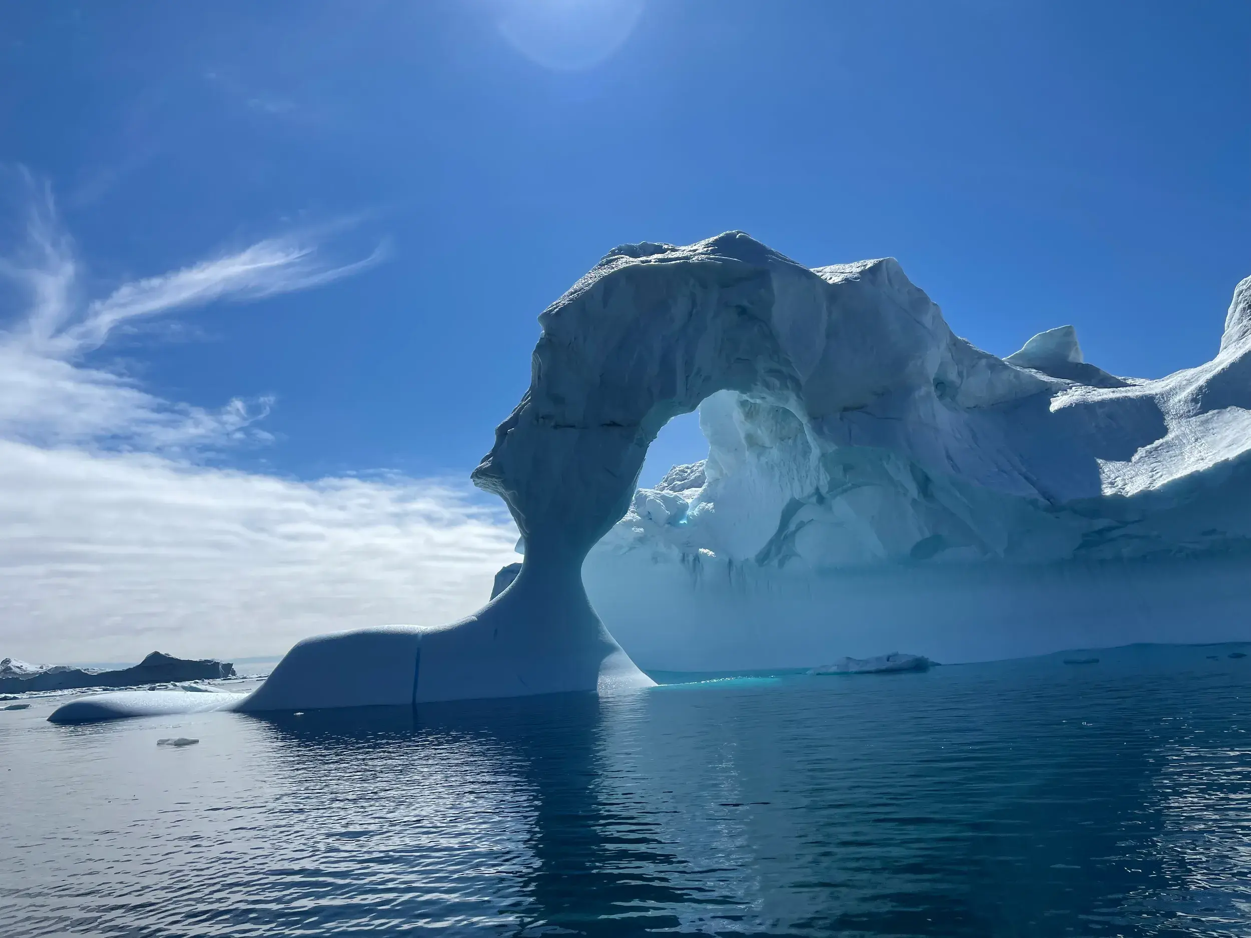 Ein skulpturaler Eisberg mit natürlichem Torbogen treibt als gigantische Skulptur im Polarstrom vor der Küste Ostgrönlands.