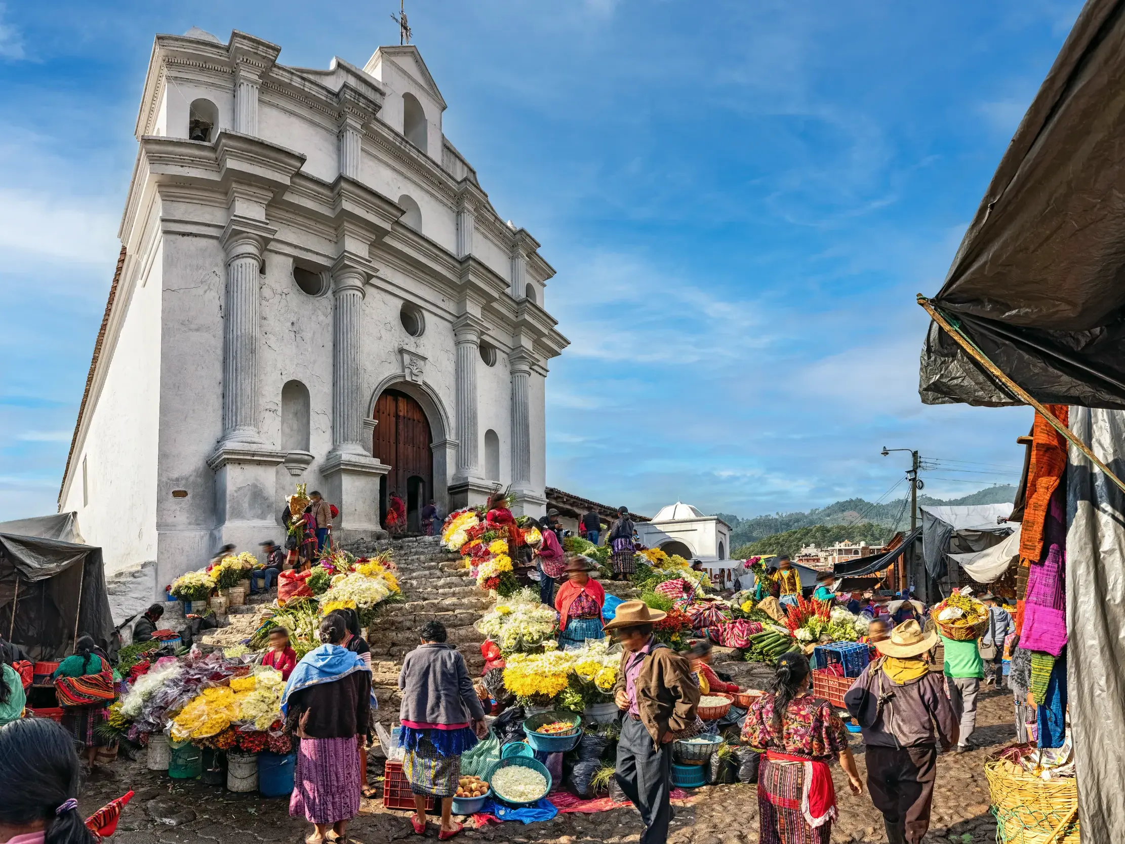 Einheimische in traditioneller Kleidung verkaufen farbenfrohe Blumen auf den Treppen der Kirche Santo Tomás in Chichicastenango.