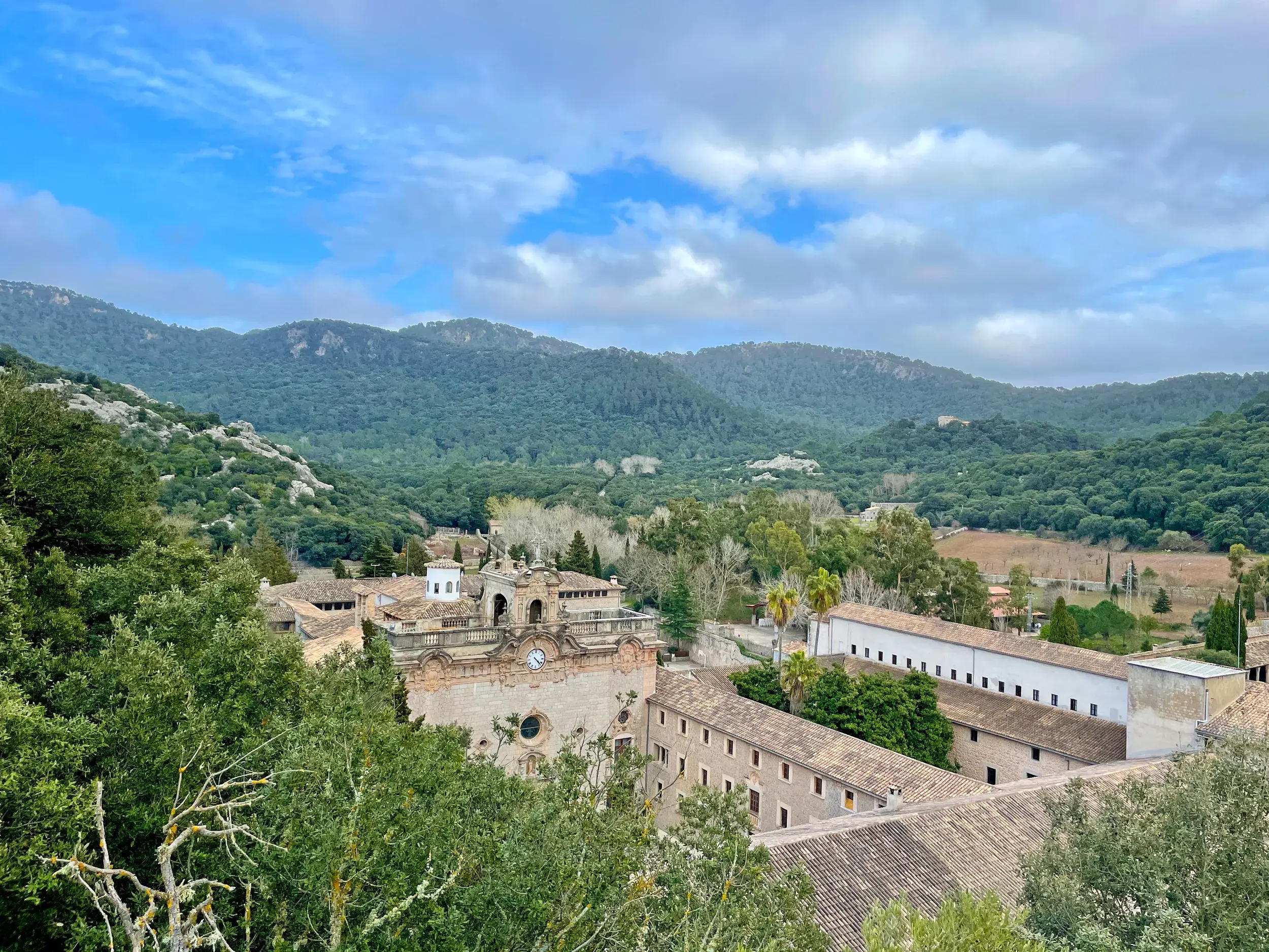 Blick auf das historische Kloster Lluc, eingebettet in die bewaldeten Berge der Serra de Tramuntana auf Mallorca.