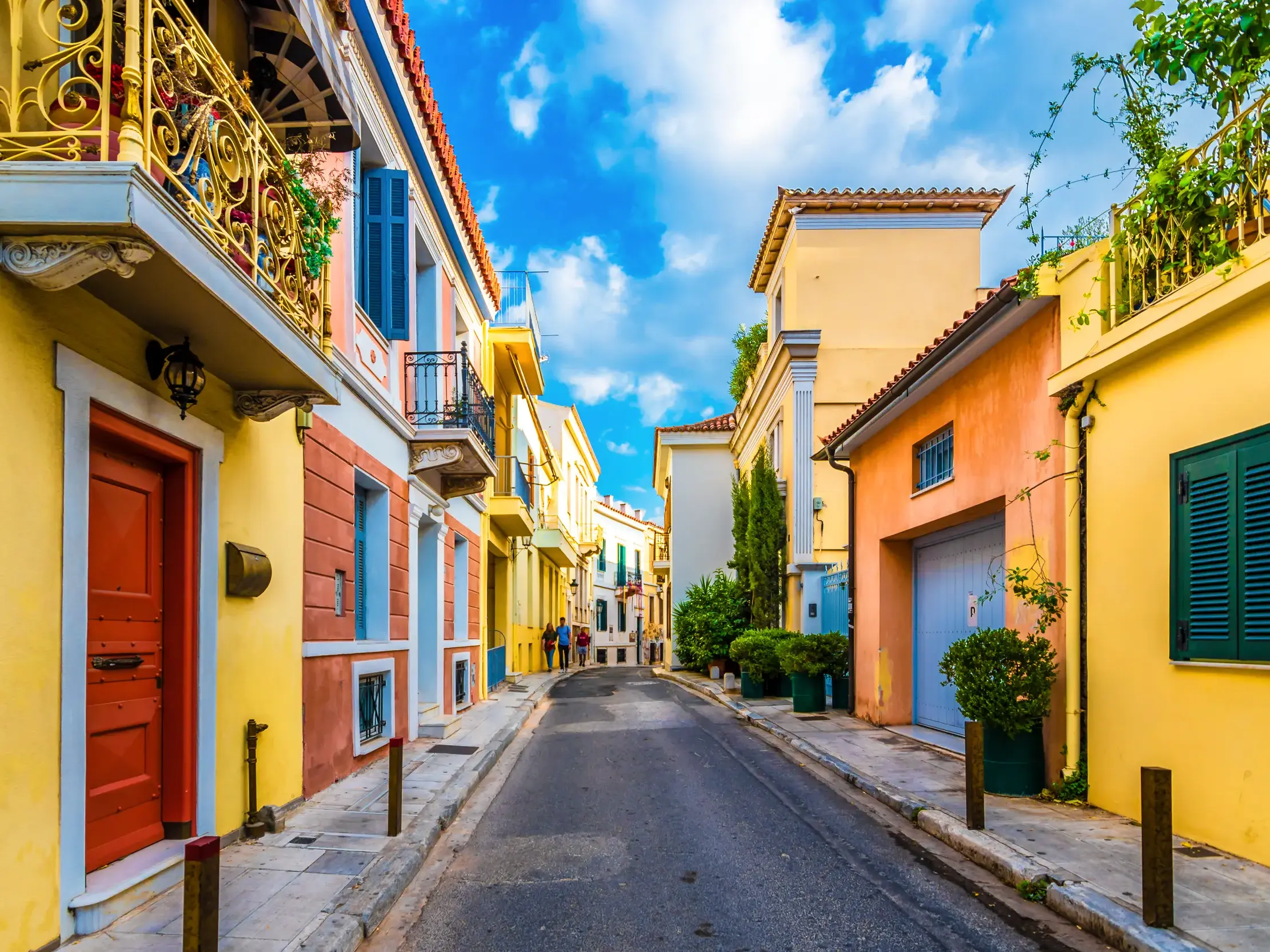 Entdeckertour durch eine malerische Gasse mit bunten Häusern und schmiedeeisernen Balkonen in der Altstadt Plaka in Athen.