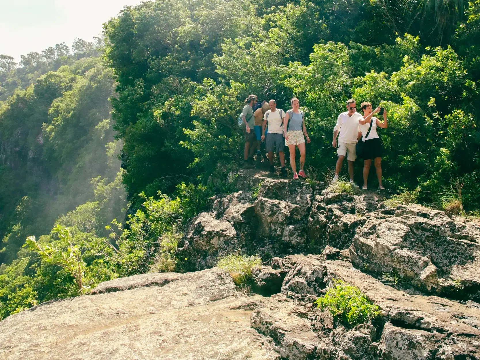 Hauser Reisegruppe macht eine Pause auf einem felsigen Aussichtspunkt während einer Wanderung im Black-River-Gorges-Nationalpark.