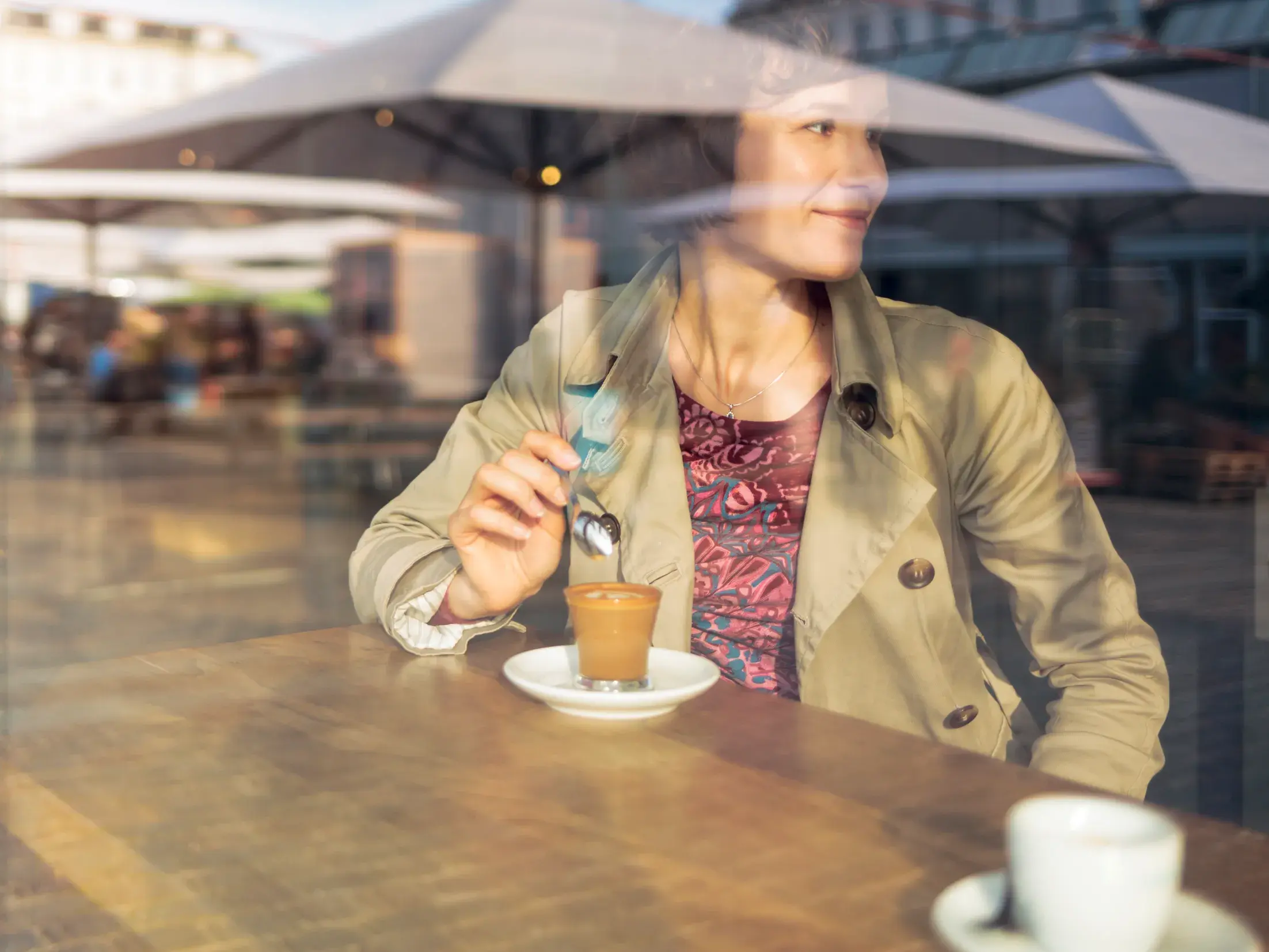 Eine Teilnehmerin einer Studiosus Studienreise genießt eine Kaffeepause in einem Café in Oslo und blickt lächelnd aus dem Fenster.