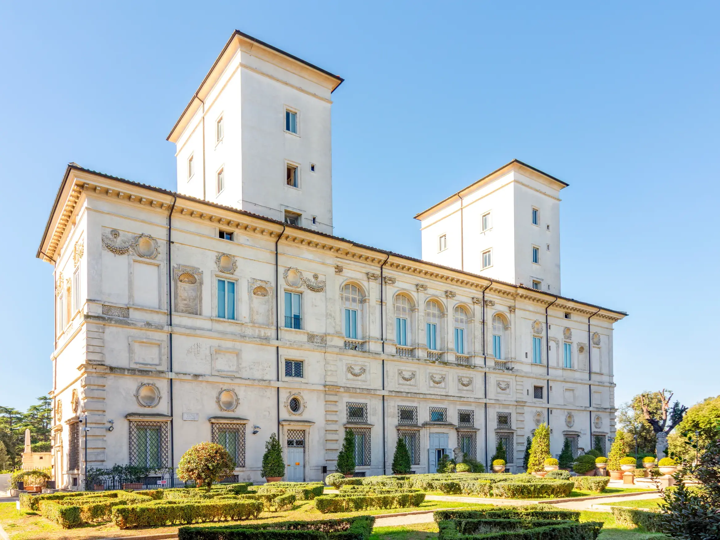 Die prachtvolle Galleria Borghese in Rom, umgeben von ihren formalen Gärten bei strahlend blauem Himmel.