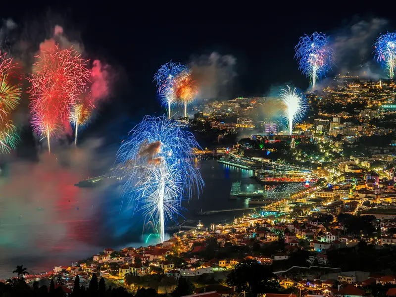 Farbenprächtiges Silvesterfeuerwerk erleuchtet den nächtlichen Himmel über der hell erleuchteten Bucht von Funchal auf Madeira.