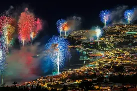 Farbenprächtiges Silvesterfeuerwerk erleuchtet den nächtlichen Himmel über der hell erleuchteten Bucht von Funchal auf Madeira.