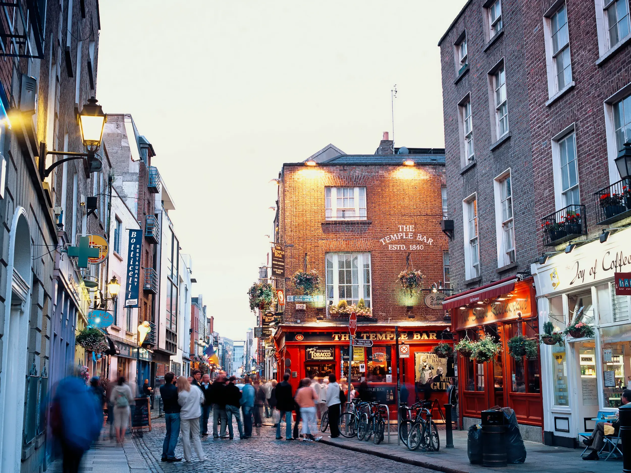 Abendliche Szene mit vielen Menschen auf der belebten Kopfsteinpflasterstraße vor dem berühmten Pub The Temple Bar in Dublin.