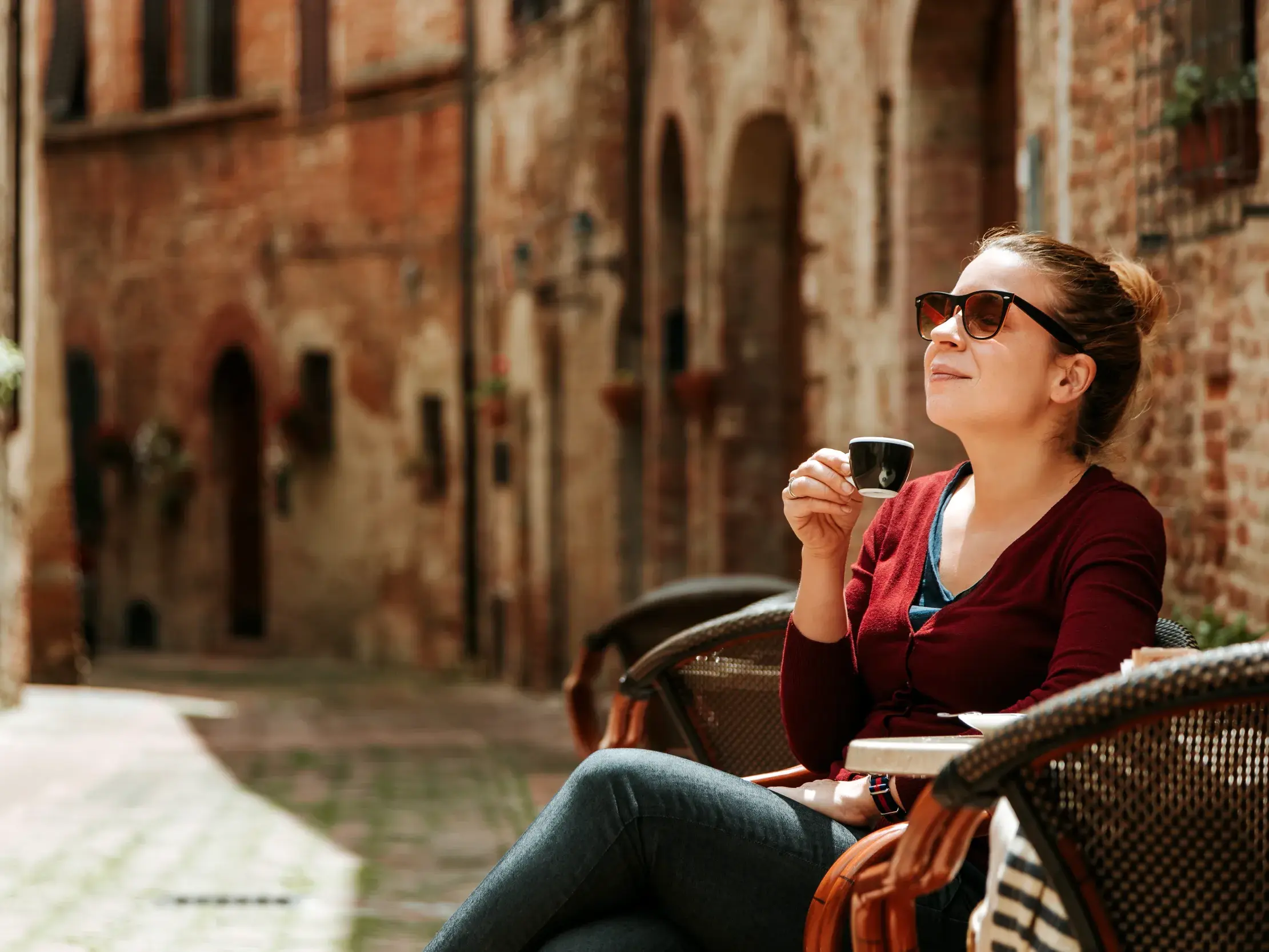 Eine Frau mit Sonnenbrille genießt das Dolcefarniente bei einem Espresso in einem Café an der Amalfiküste.