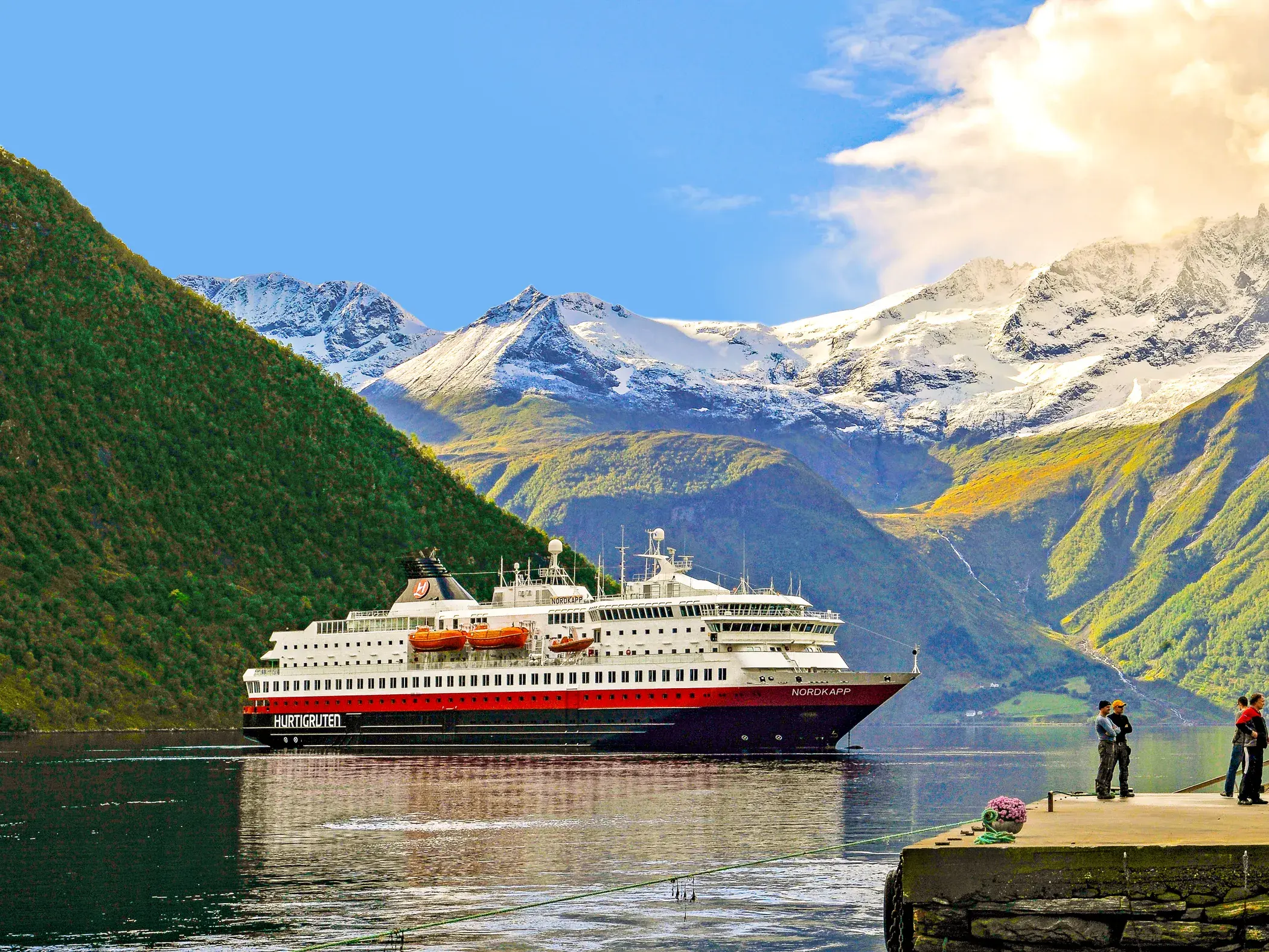 Das Hurtigruten Postschiff MS Nordkapp auf seiner Reise durch einen Fjord in Norwegen, vorbei an schneebedeckten Gipfeln.