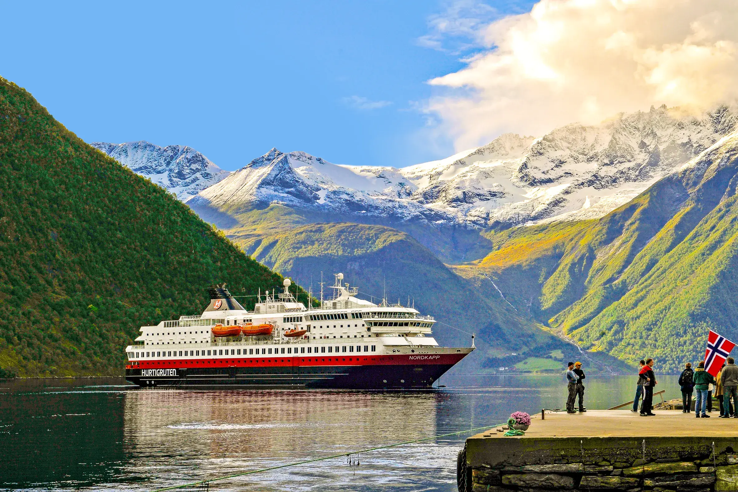 Das Hurtigruten Postschiff MS Nordkapp auf seiner Reise durch einen Fjord in Norwegen, vorbei an schneebedeckten Gipfeln.