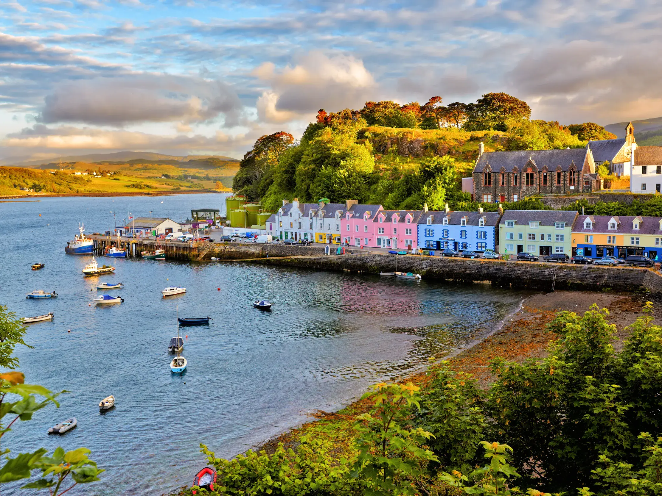 Idyllischer Hafen von Portree auf der Isle of Skye mit seiner bunten Häuserzeile und kleinen Booten im Wasser.