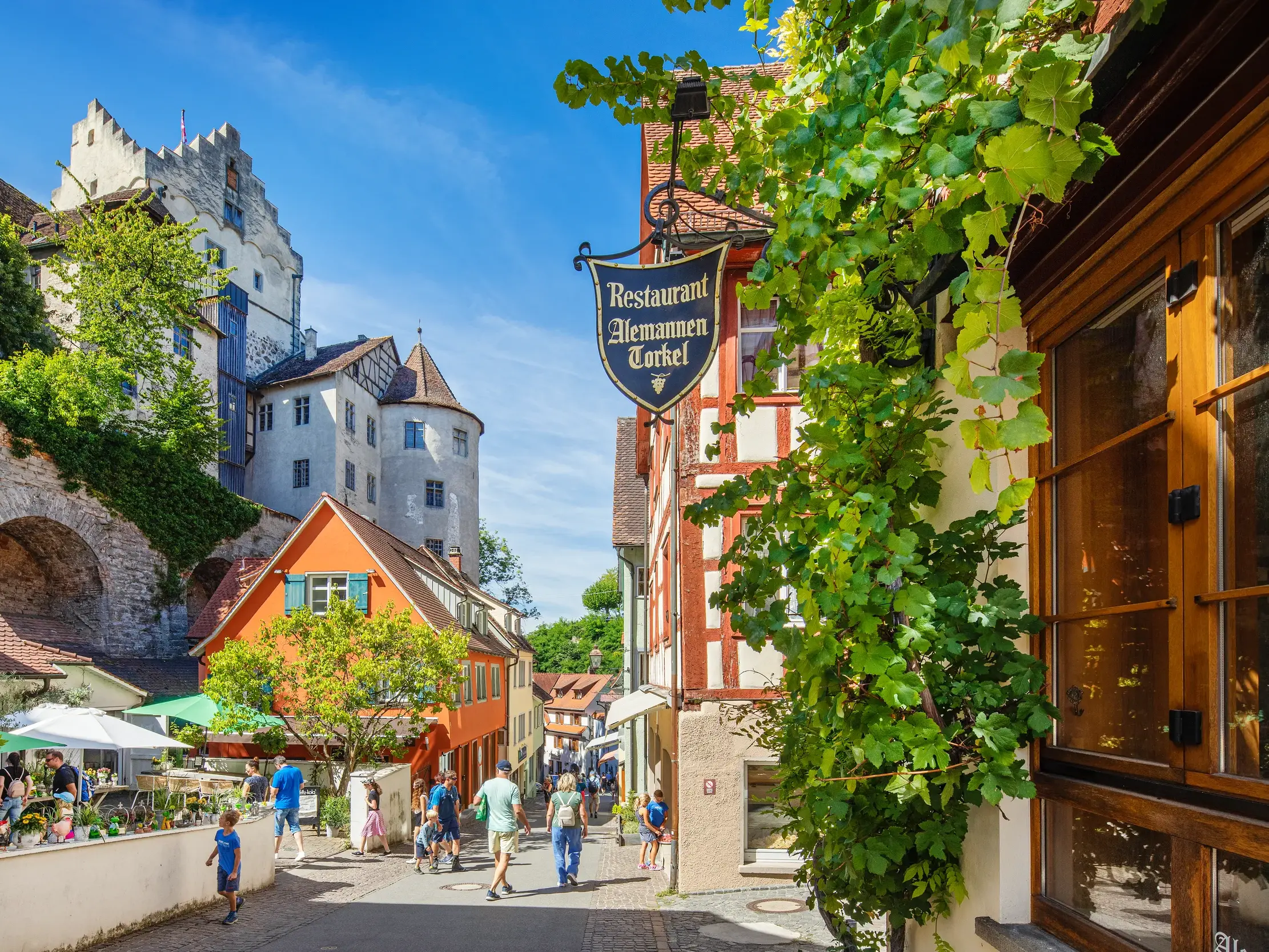 Spaziergänger in den malerischen Gassen der Altstadt von Meersburg mit Blick auf die historische Burg.