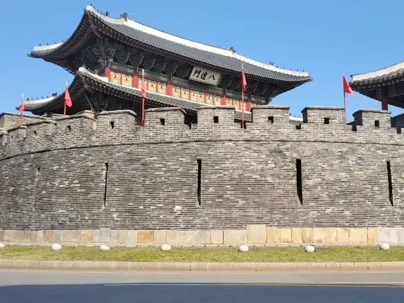 Die historische Hwaseong-Festung in Suwon, ein UNESCO-Weltkulturerbe, mit dem imposanten Paldalmun-Tor unter blauem Himmel.