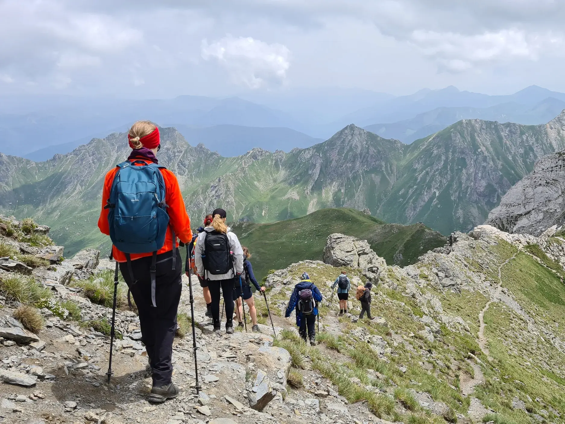 Eine Wandergruppe beim Trekking auf einem felsigen Grat mit Panoramablick auf die albanische Bergwelt des Korab-Gebirges.