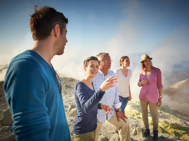 Eine Studiosus-Reiseleiterin erklärt einer kleinen Gruppe die dampfende Kraterlandschaft des Ätna.