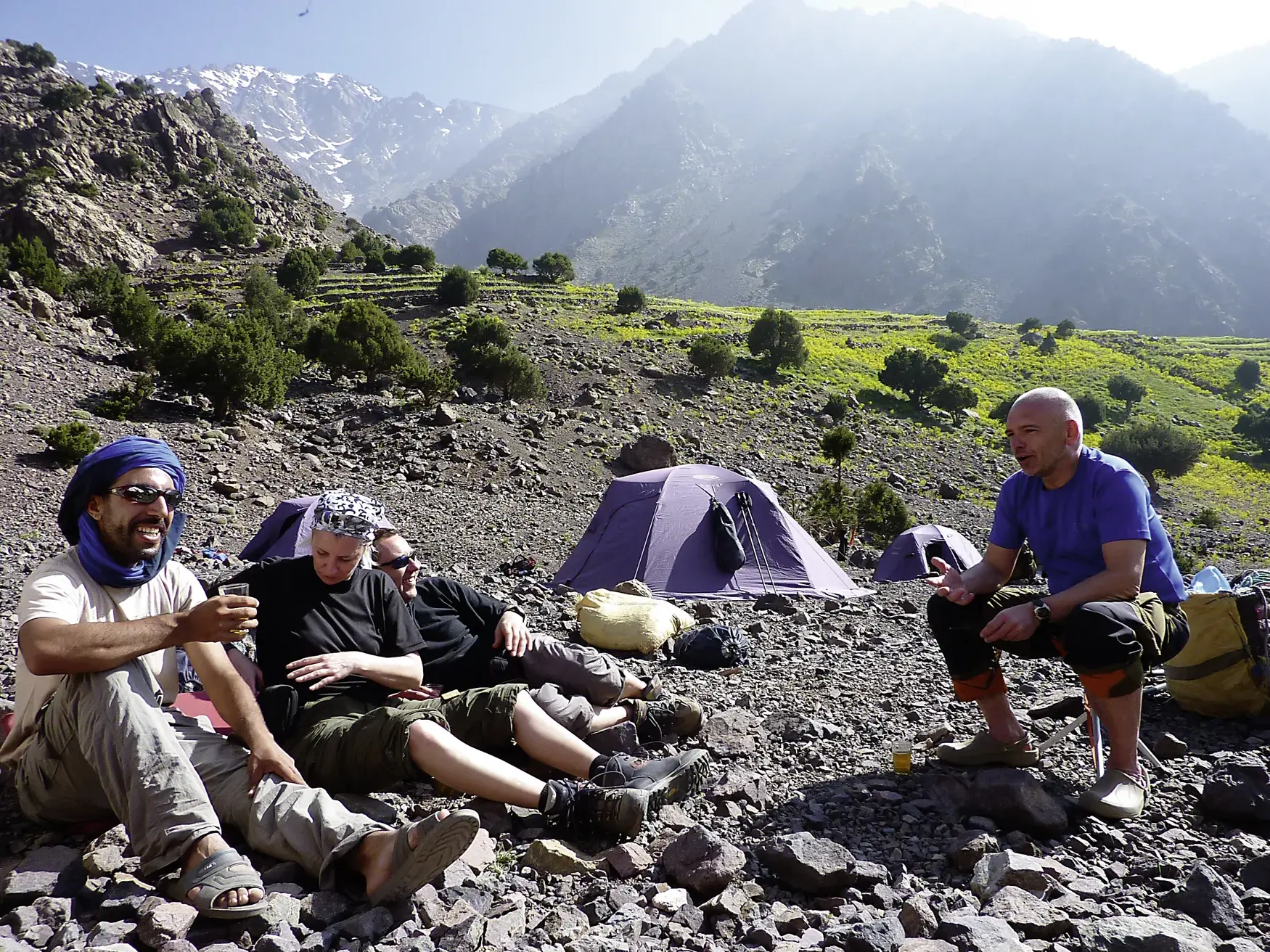 Eine Hauser-Reisegruppe und ein lokaler Guide entspannen im Zeltlager während des Trekkings im Hohen Atlas in Marokko.