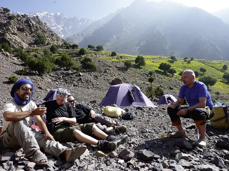 Eine Hauser-Reisegruppe und ein lokaler Guide entspannen im Zeltlager während des Trekkings im Hohen Atlas in Marokko.