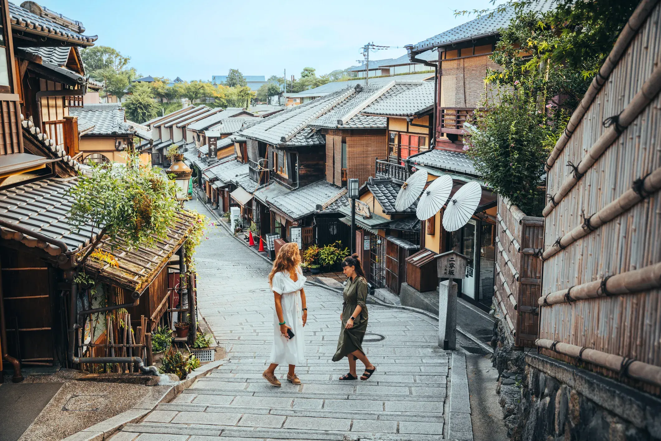 Zwei Alleinreisende erkunden die traditionellen Holzhäuser und Steinstufen im malerischen Gion-Viertel in Kyoto.