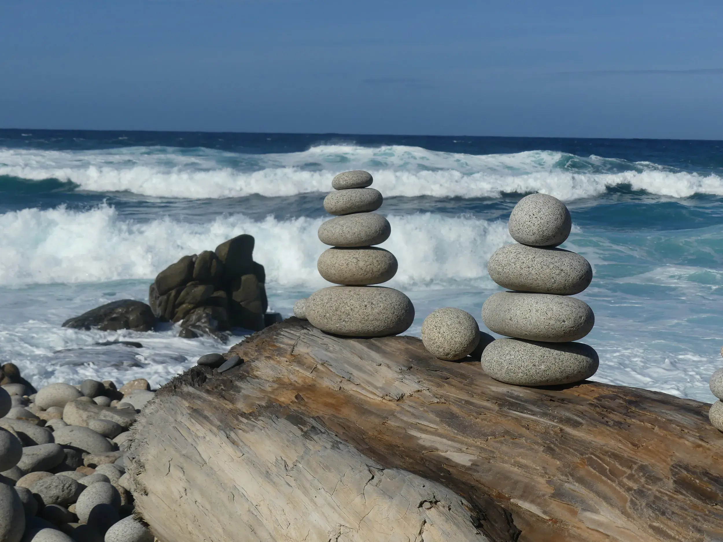 Steintürme aus Granitfelsen am Capo Pecora auf Sardinien, balancierend auf Treibholz vor dem tosenden Meer.