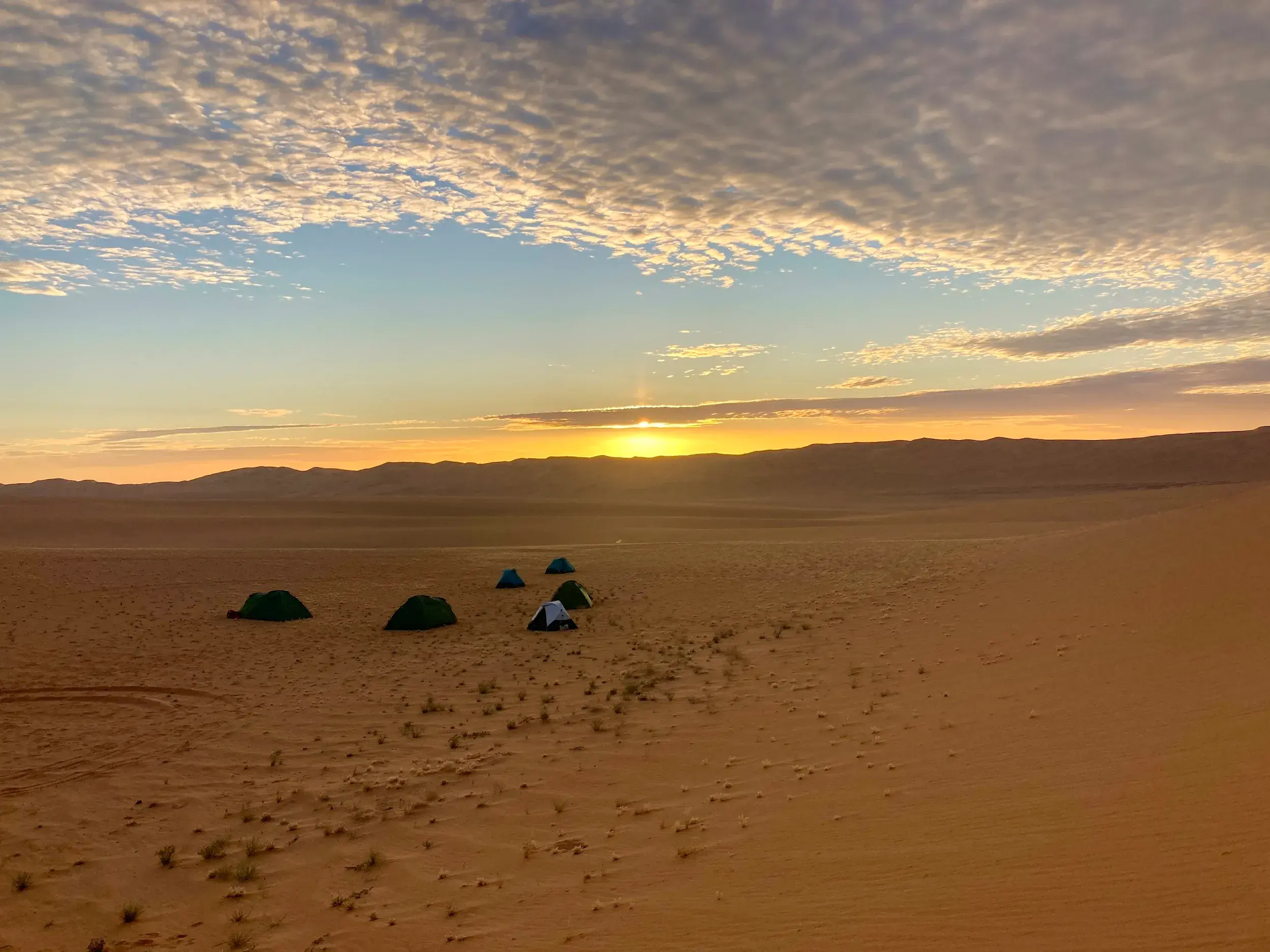 Zeltlager einer Hauser-Trekkinggruppe bei Sonnenuntergang in der weiten Dünenlandschaft des Tassili n'Ajjer Nationalparks.