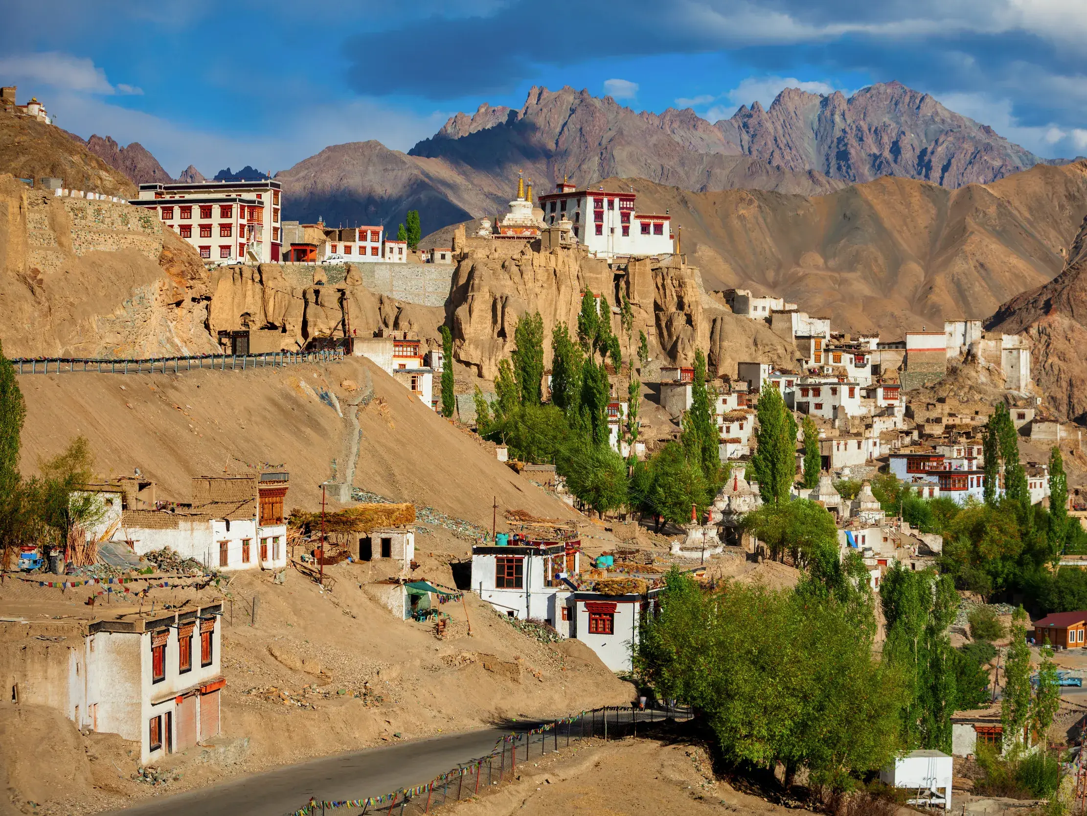 Das eindrucksvolle Kloster Lamayuru thront auf einem Felsvorsprung über dem Dorf, umgeben von der kargen Bergwelt Ladakhs unter blauem Himmel.