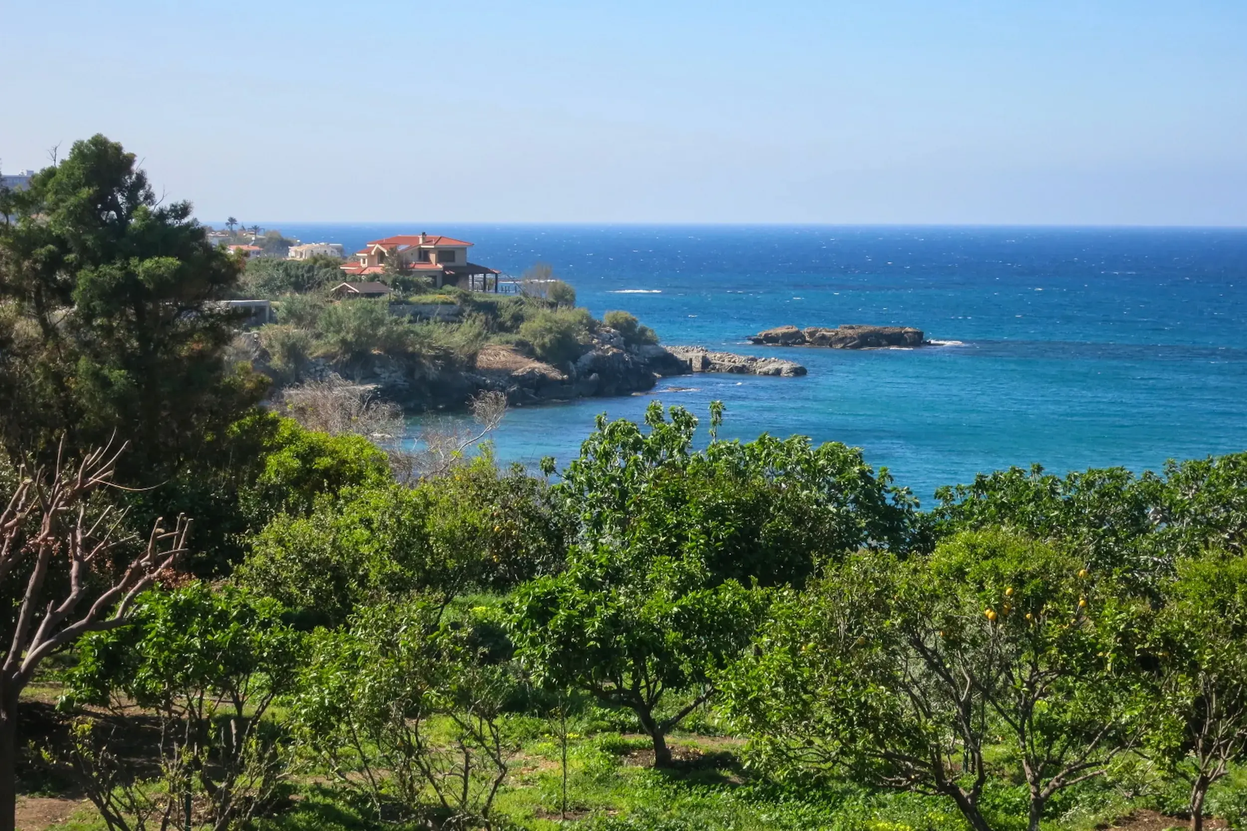 Panoramablick vom Beşparmak-Trail auf die Küste Nordzyperns mit mediterraner Villa und dem tiefblauen Mittelmeer.