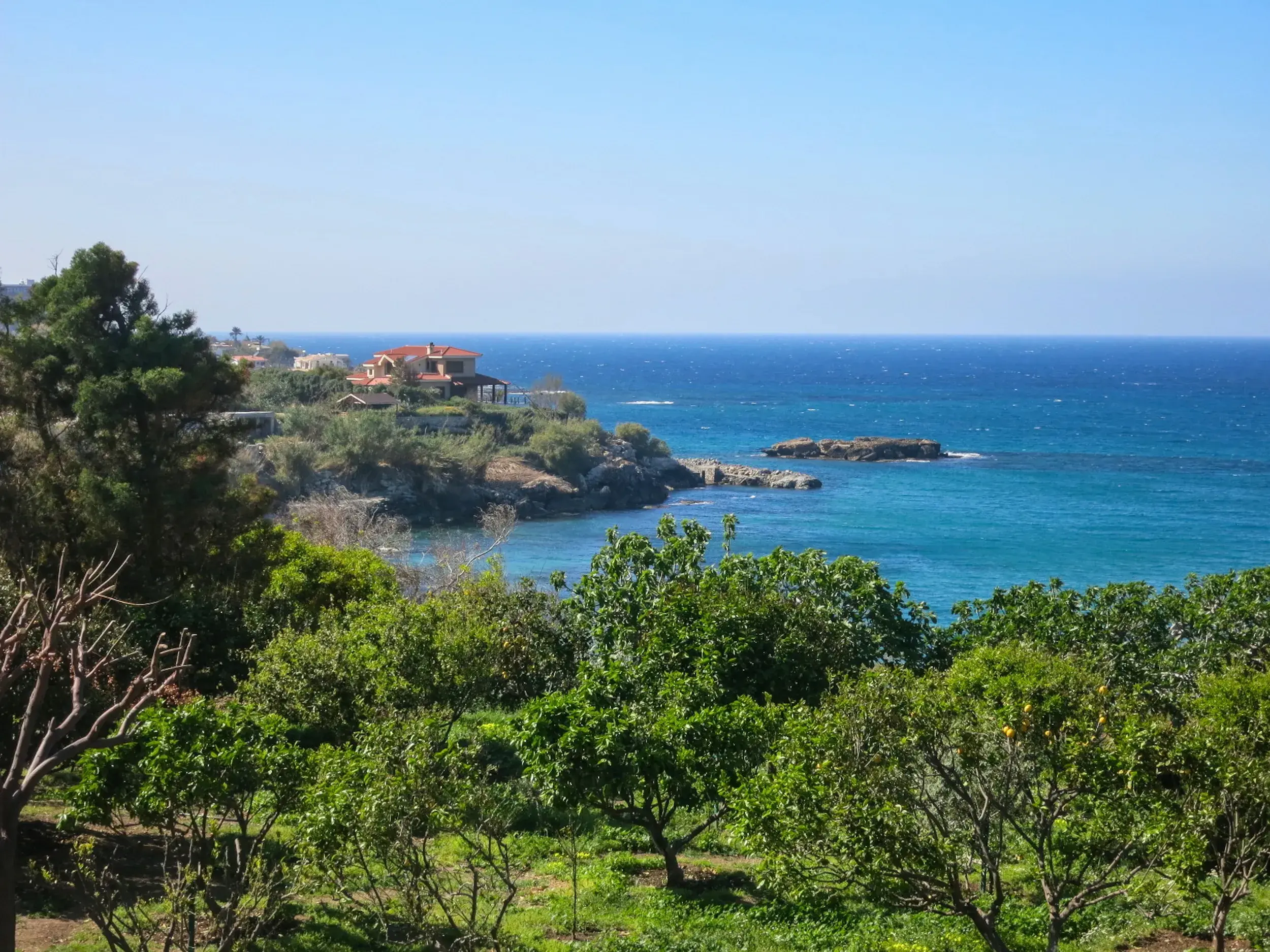 Panoramablick vom Beşparmak-Trail auf die Küste Nordzyperns mit mediterraner Villa und dem tiefblauen Mittelmeer.