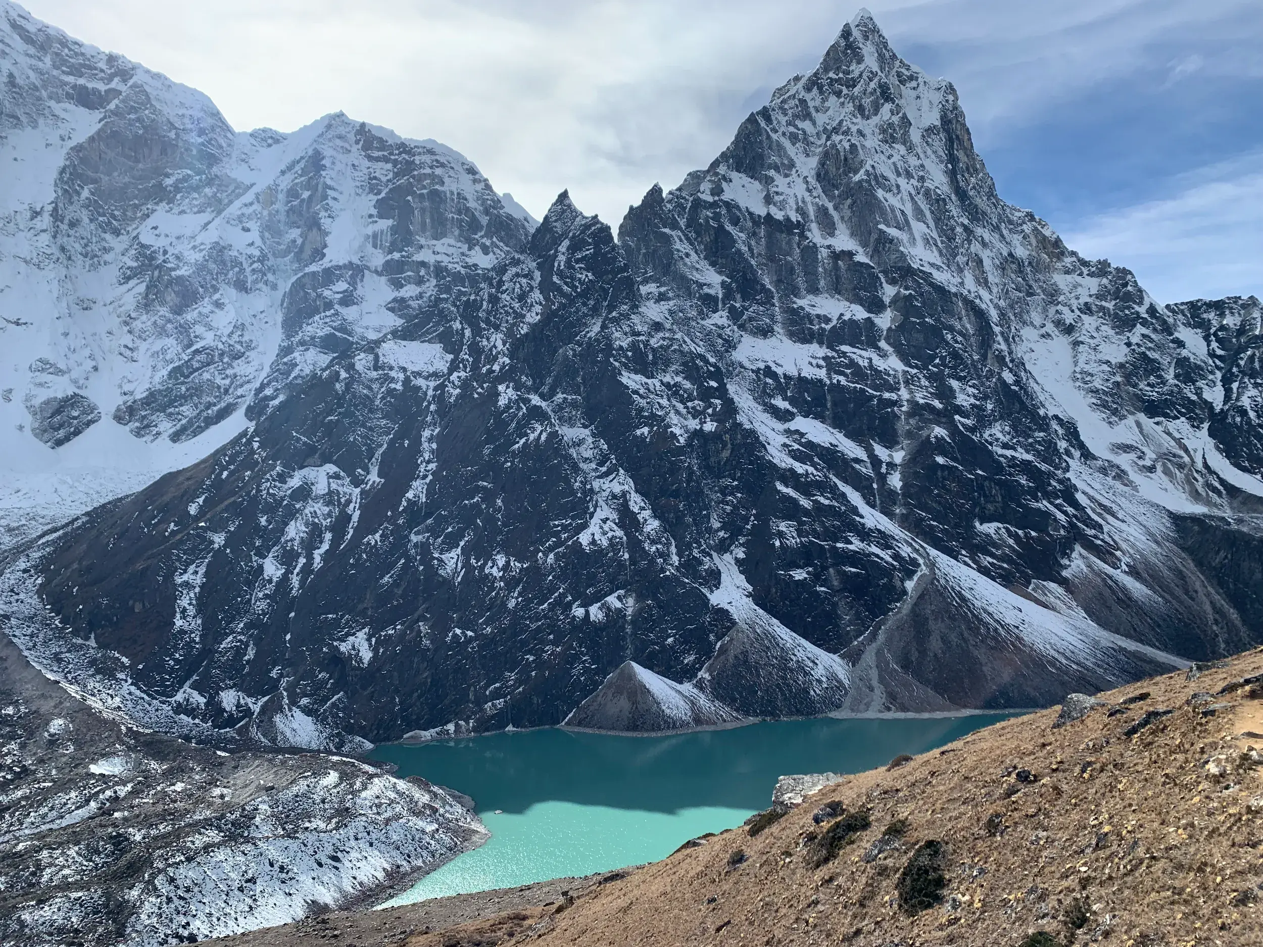 Atemberaubender Ausblick beim Trekking in Nepal auf den türkisfarbenen Gokyo-See vor der Kulisse schneebedeckter Himalaya-Gipfel.
