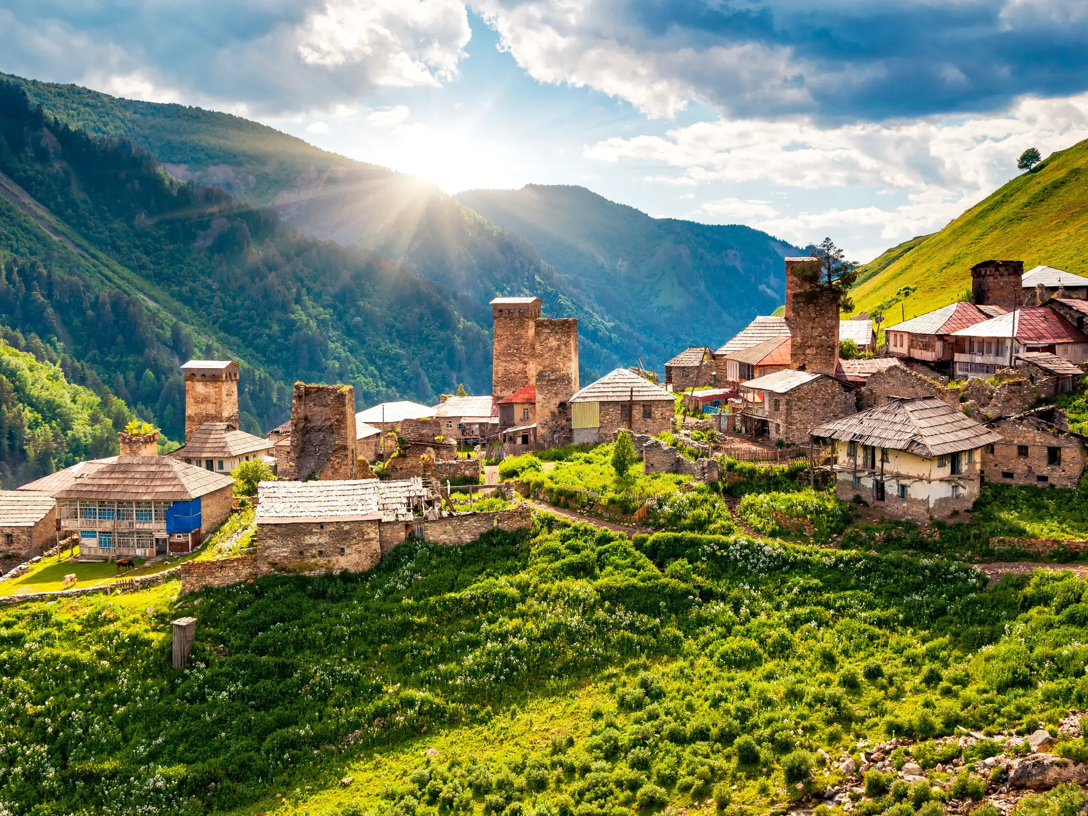 Historische Wehrtürme im Bergdorf Uschguli in Swanetien, Georgien, umgeben von grünen Wiesen und Bergen des Kaukasus.