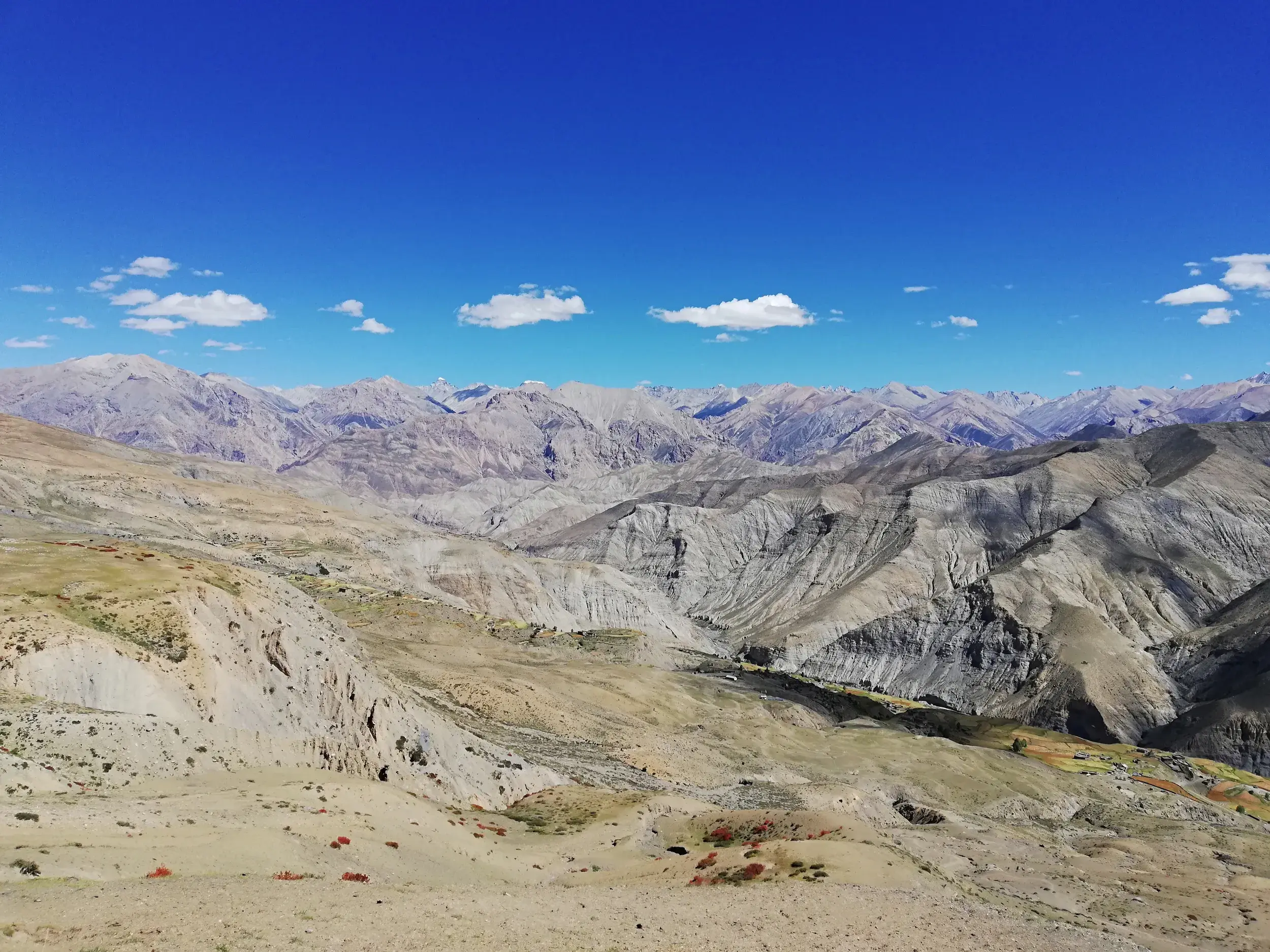 Panoramablick über die trockenen, zerklüfteten Täler und Berge des Inneren Dolpo in Nepal unter strahlend blauem Himmel.