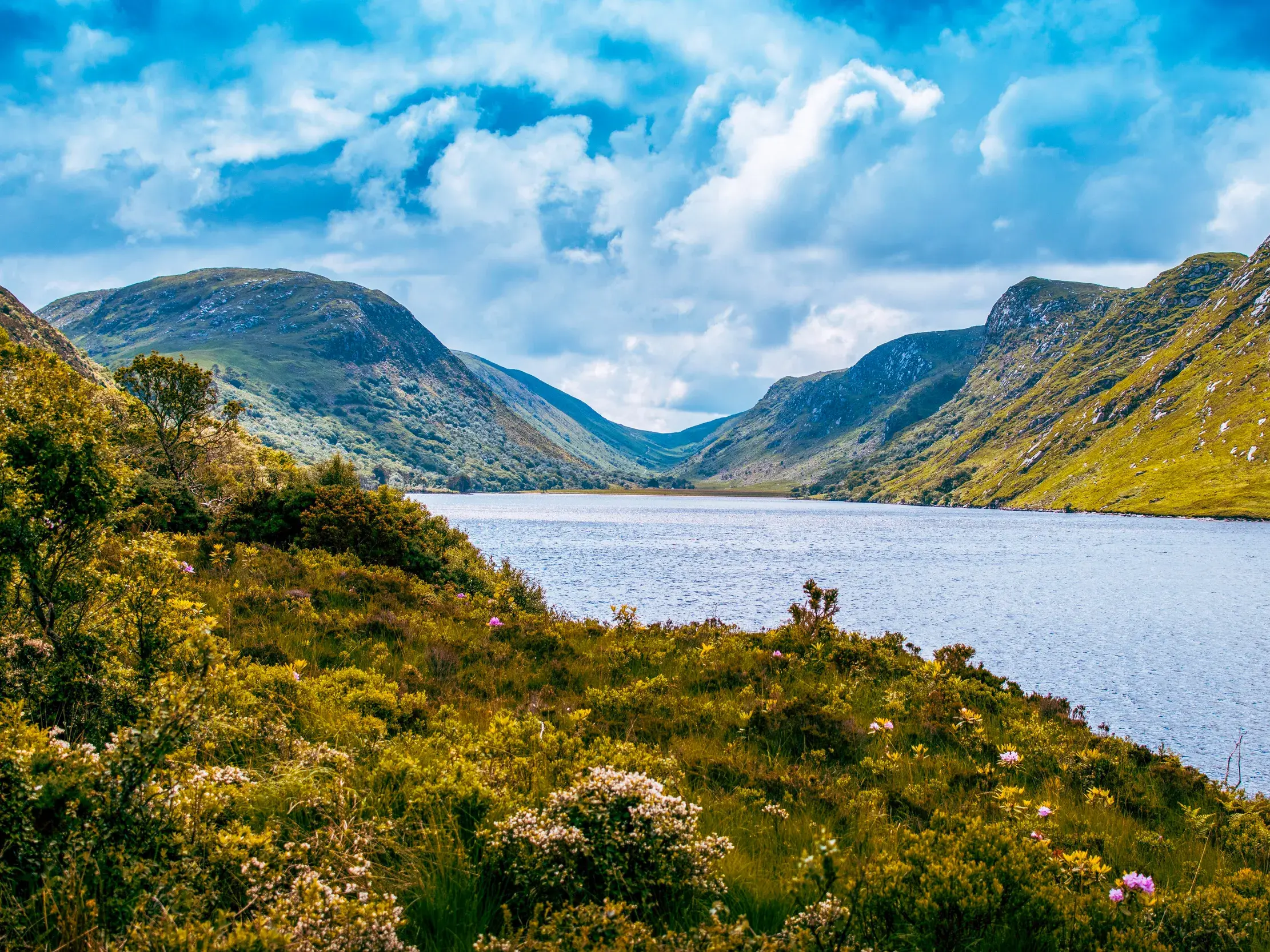 Malerischer Blick auf den von steilen, grünen Bergen umgebenen See Lough Beagh bei einer Wanderung im Glenveagh Nationalpark.